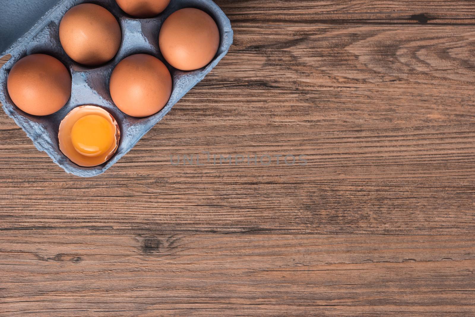 Cardboard egg box on wooden table. Top view with copy space by AnaMarques