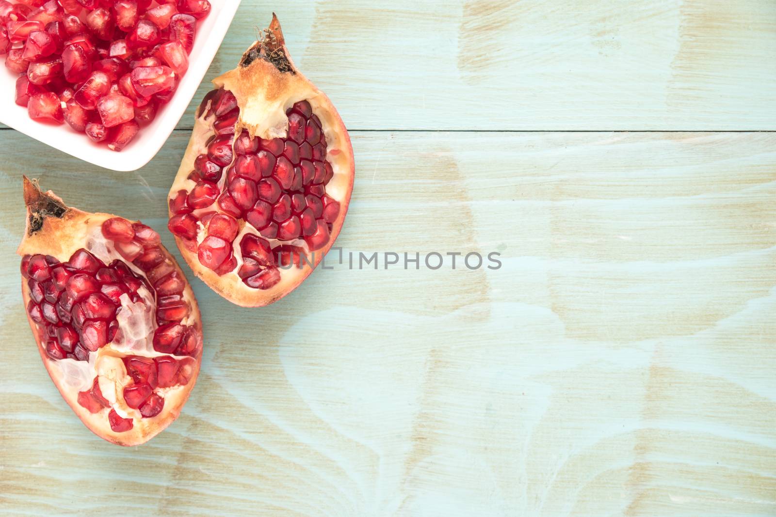 Pomegranates over grunge wooden background by AnaMarques