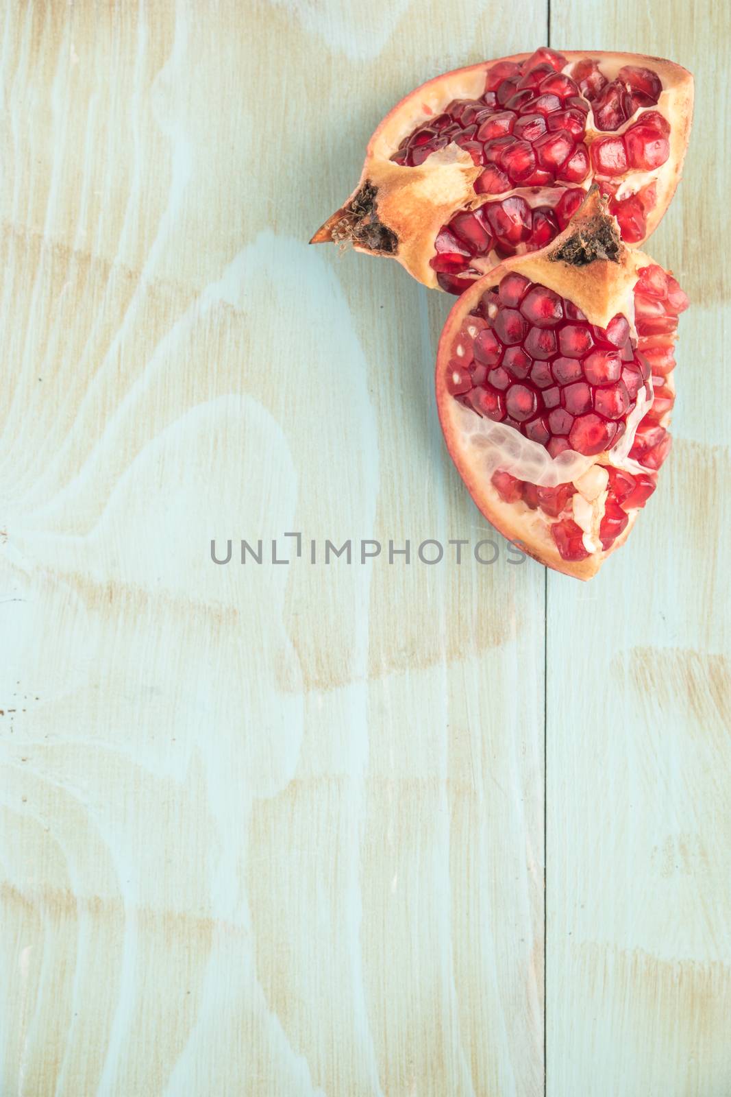 Red ripe peeled pomegranate on rustic wood board background. Top view, copy space