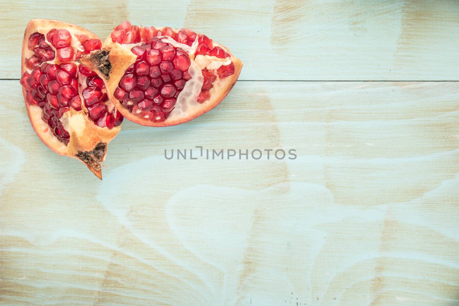 Red ripe peeled pomegranate on rustic wood board background. Top view, copy space