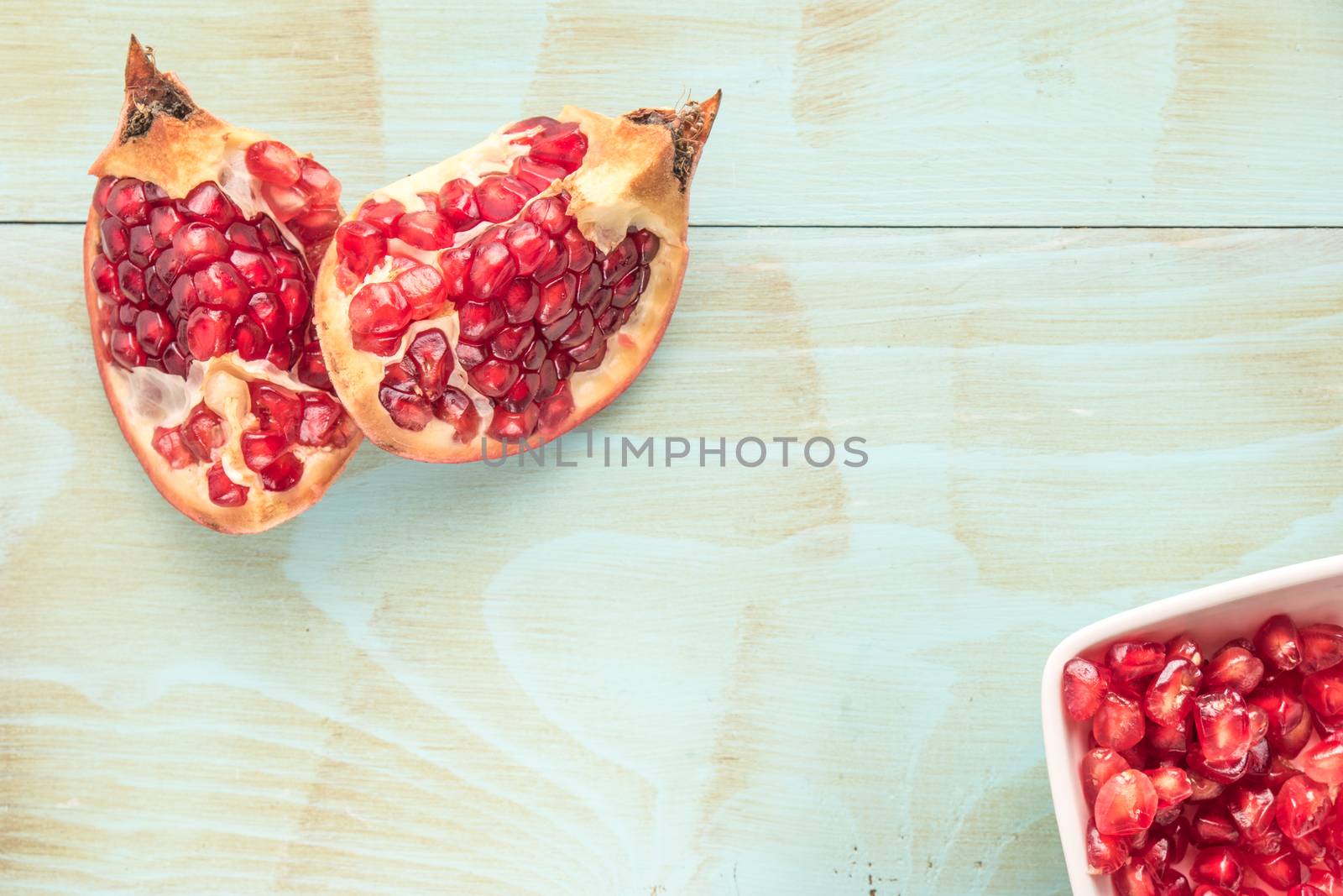 Pomegranates over grunge wooden background by AnaMarques