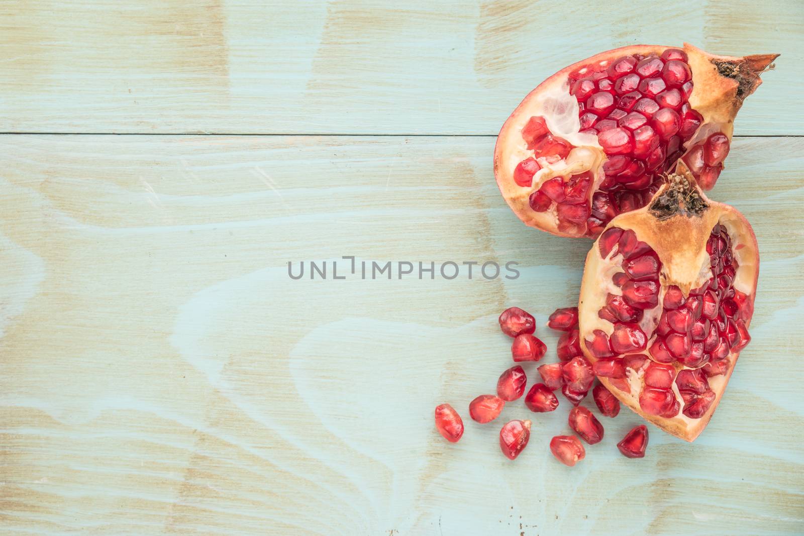 Red ripe peeled pomegranate on rustic wood board background. Top view, copy space