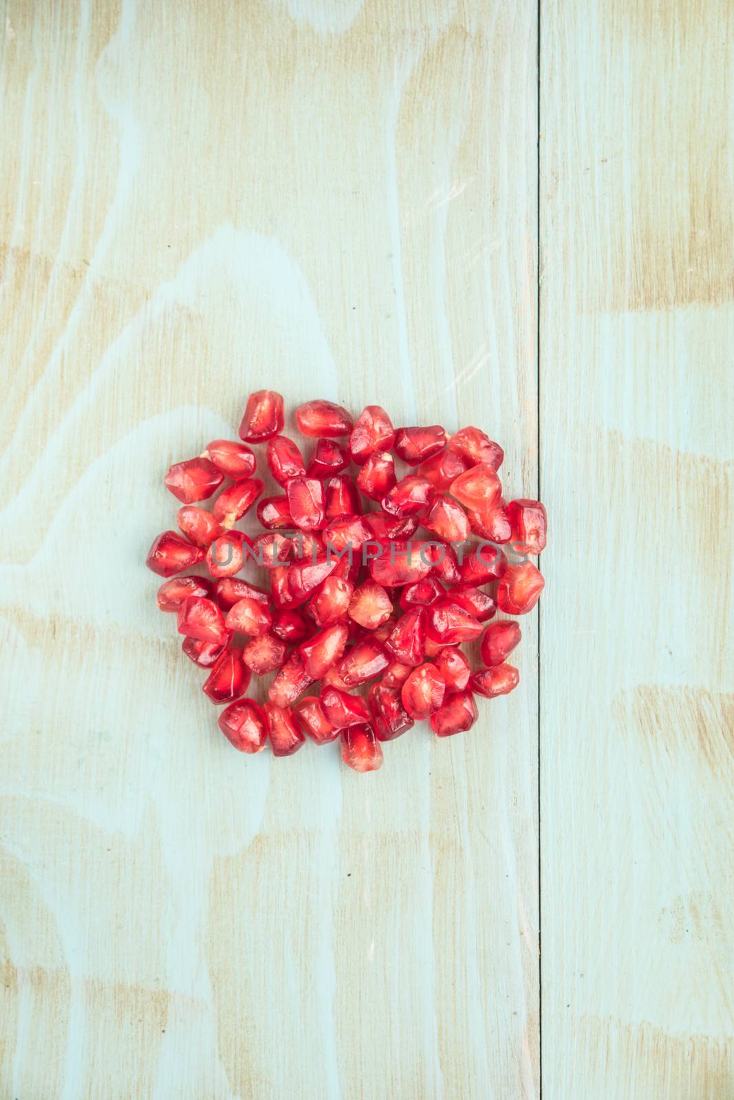 Red ripe peeled pomegranate on rustic wood board background. Top view, copy space