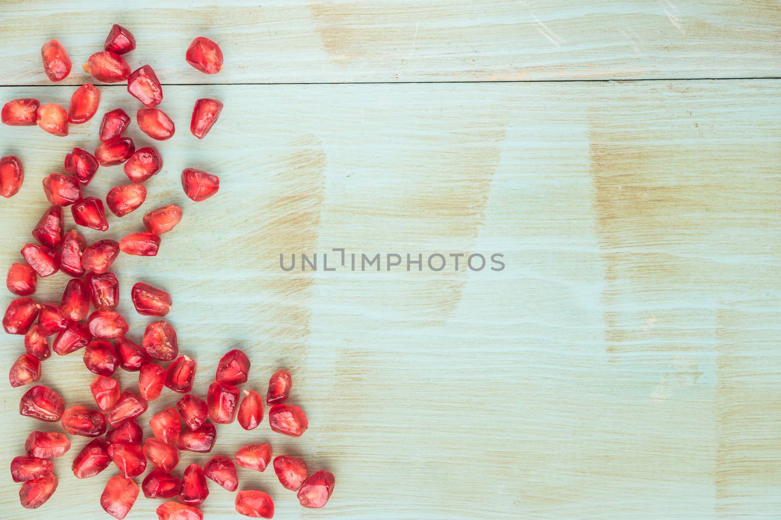 Red ripe peeled pomegranate on rustic wood board background. Top view, copy space