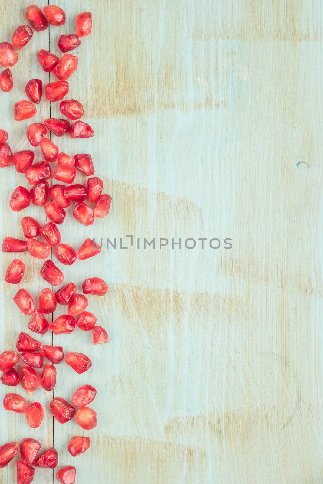 Red ripe peeled pomegranate on rustic wood board background. Top view, copy space