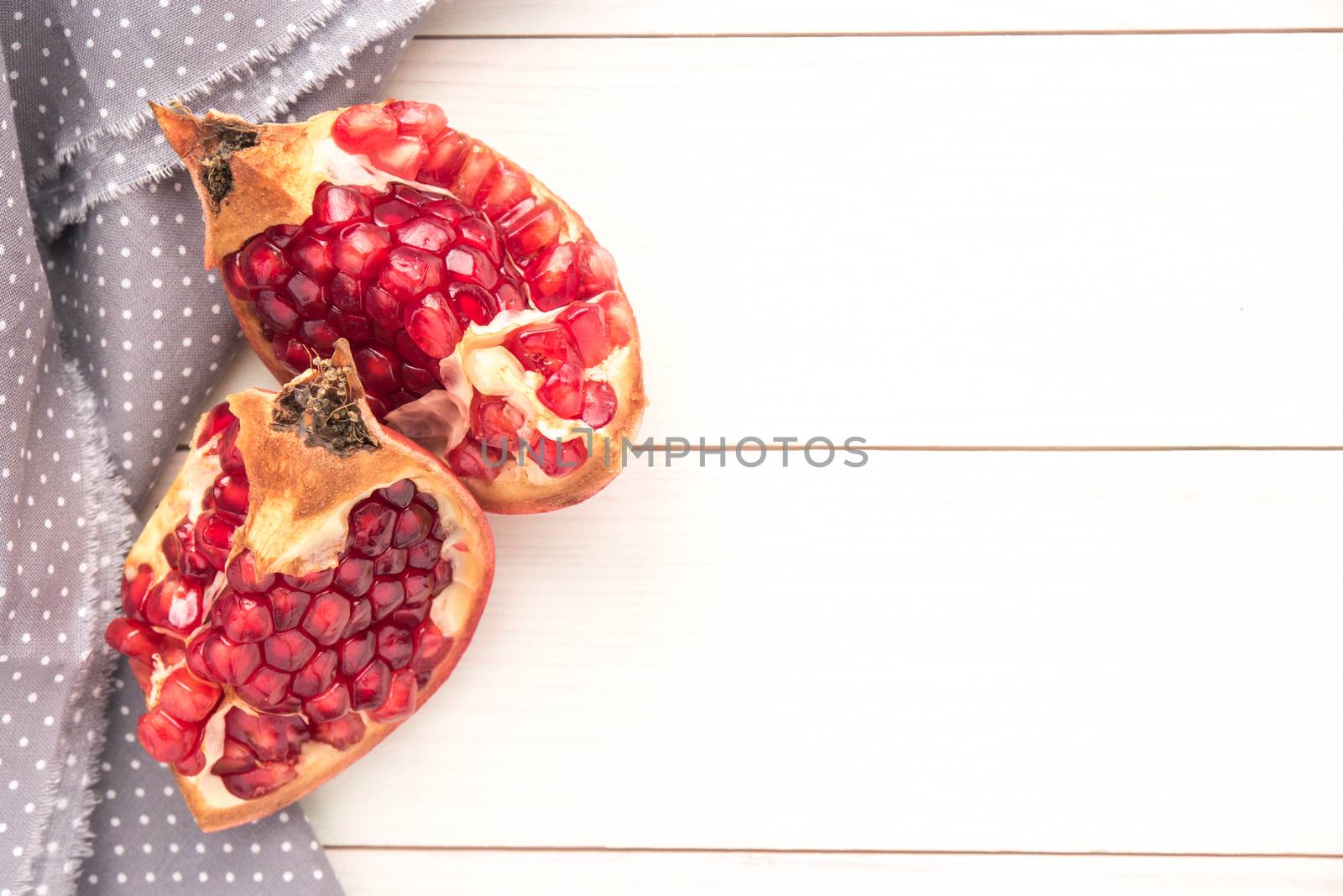 Red ripe peeled pomegranate on rustic wood board background. Top view, copy space