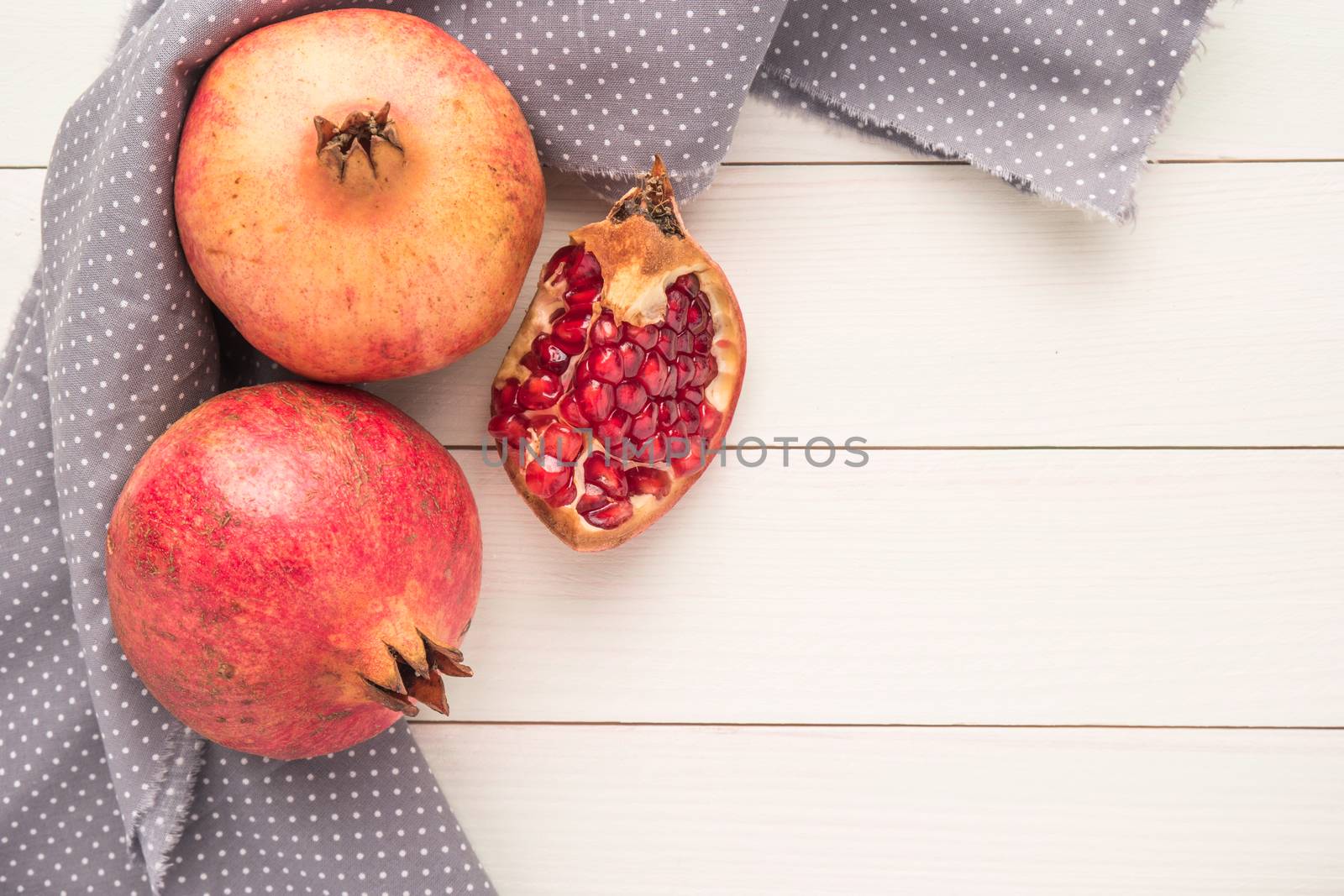 Red ripe peeled pomegranate on rustic wood board background. Top view, copy space