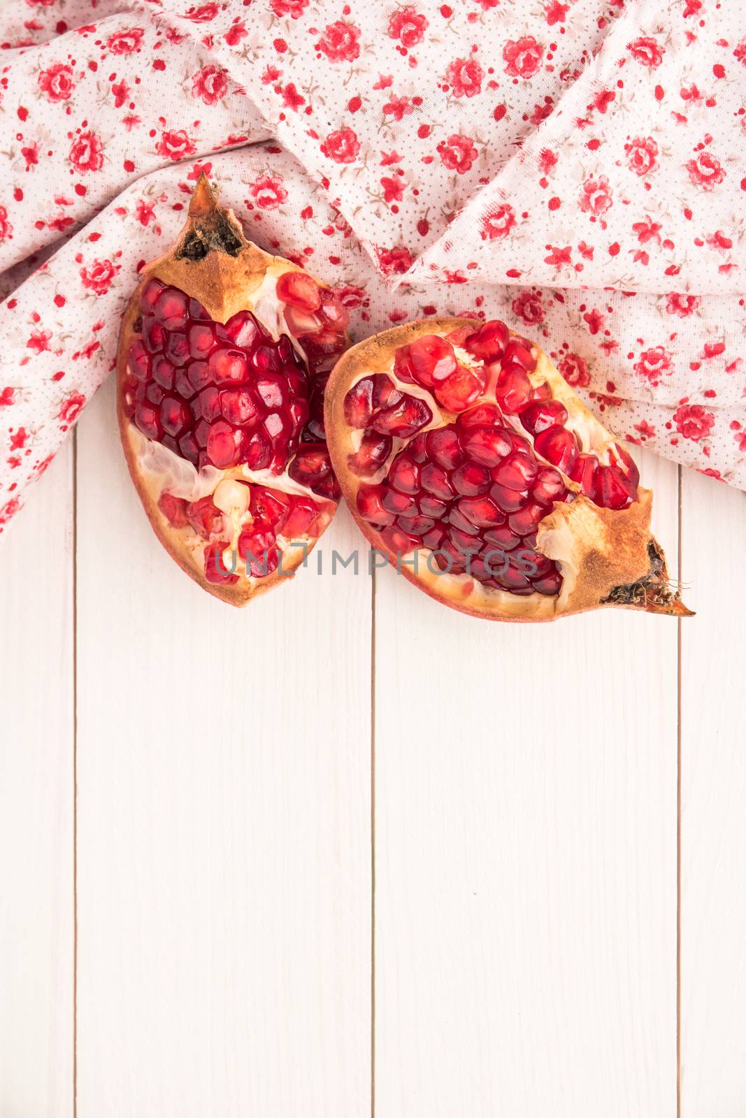 Red ripe peeled pomegranate on rustic wood board background. Top view, copy space