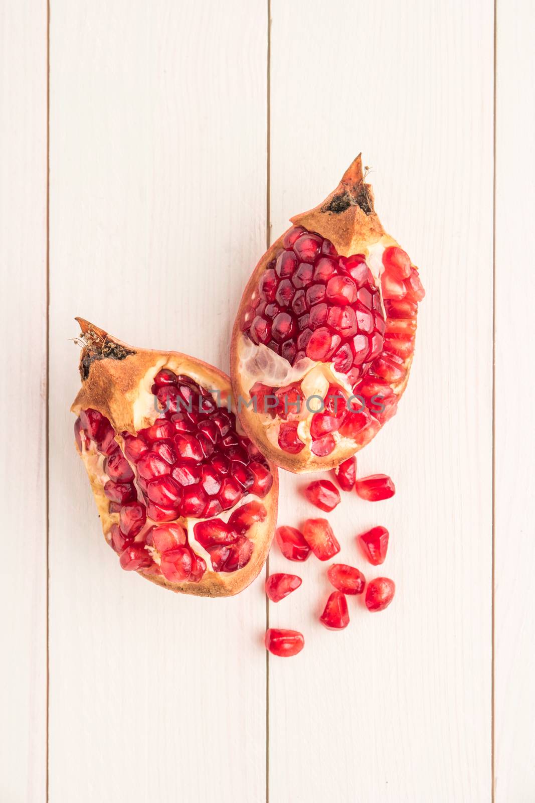 Red ripe peeled pomegranate on rustic wood board background. Top view, copy space