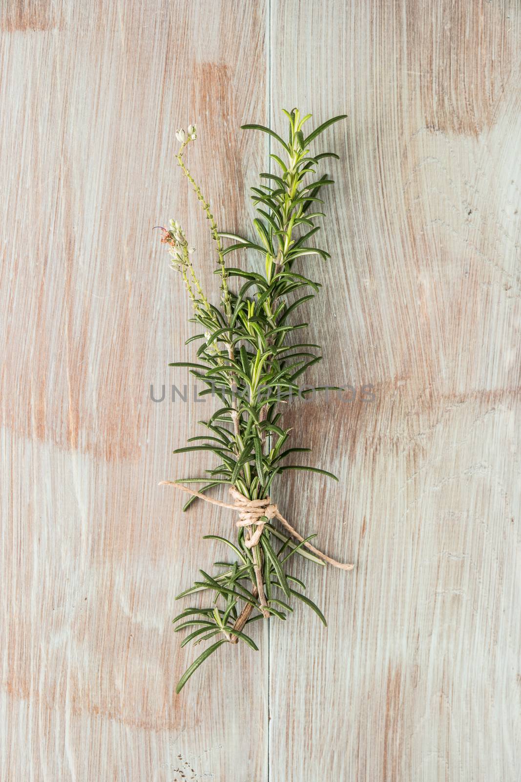 Bunch of fresh of garden rosemary on wooden table, rustic style, fresh organic herbs. Top view with copy space