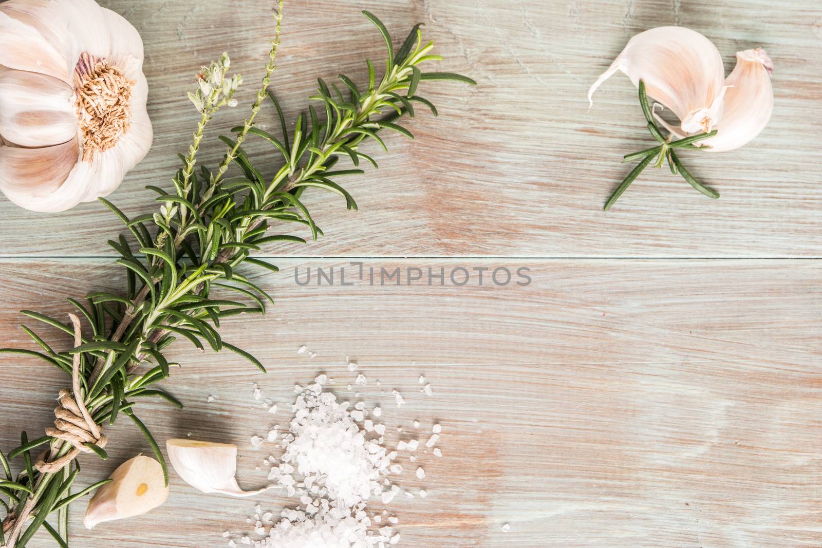 Bunch of fresh of garden rosemary on wooden table, rustic style, fresh organic herbs with salt and garlic. Top view with copy space