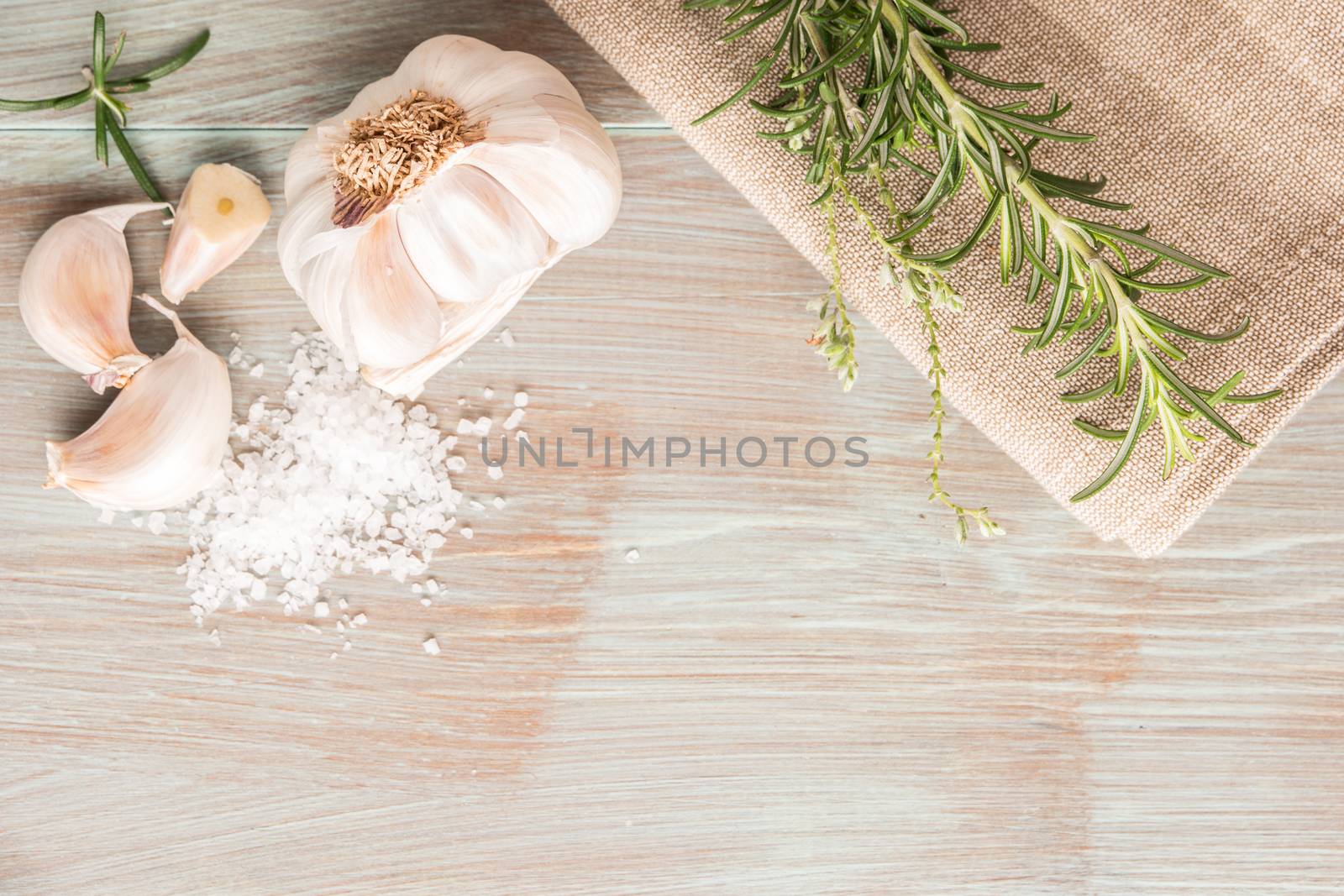 Bunch of fresh of garden rosemary on wooden table, rustic style, fresh organic herbs with salt and garlic. Top view with copy space