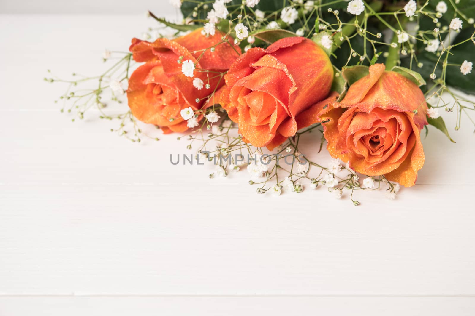 A bouquet of orange roses and gypsophila on wooden table. Copy s by AnaMarques