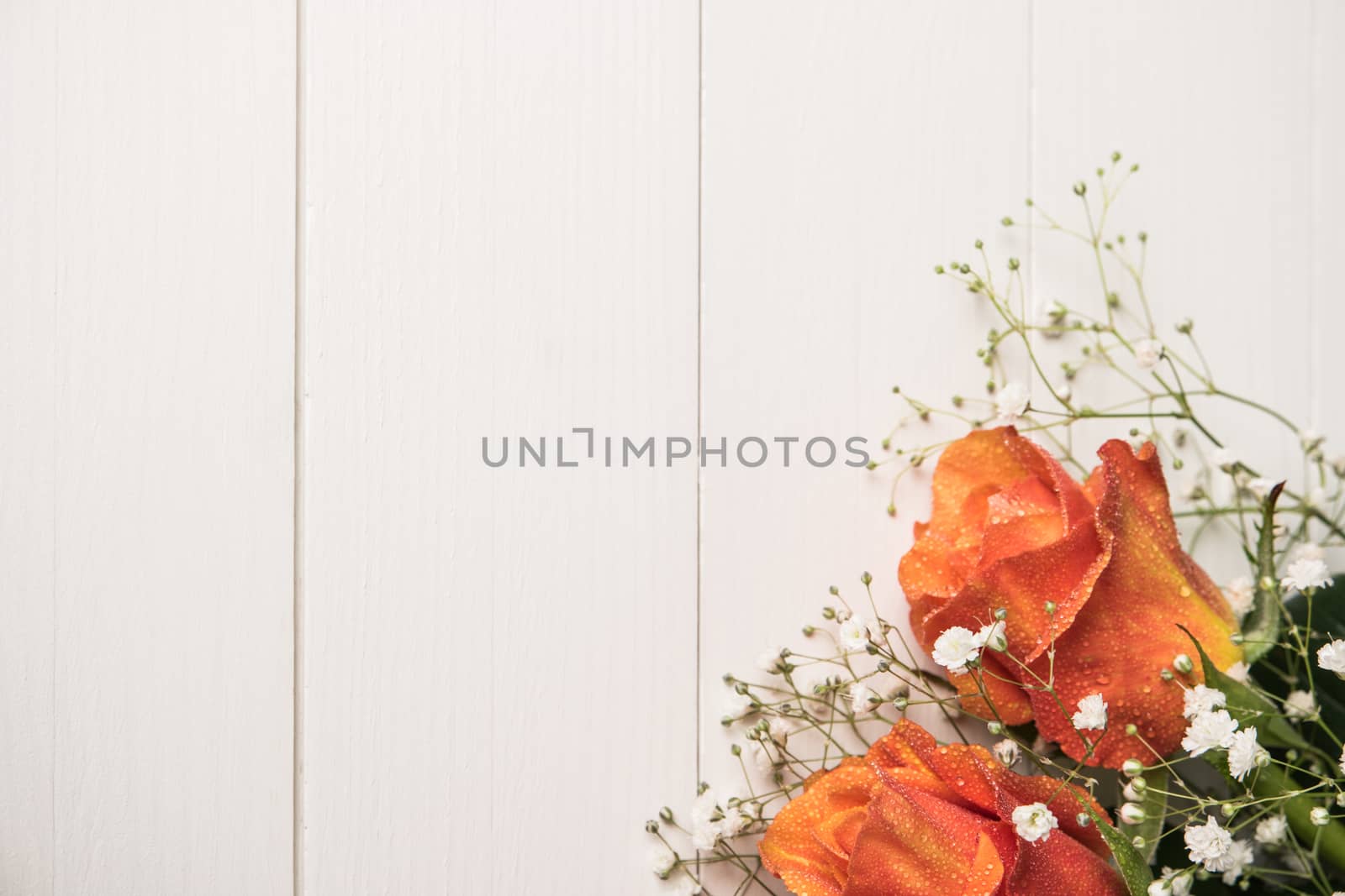 A bouquet of orange roses and gypsophila on wooden table. Copy s by AnaMarques