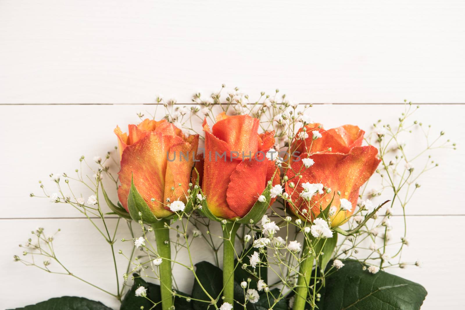 A bouquet of orange roses and gypsophila on wooden table. Copy s by AnaMarques