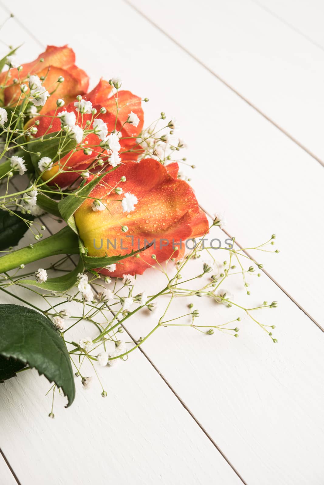 A bouquet of orange roses and gypsophila on wooden table. Copy s by AnaMarques