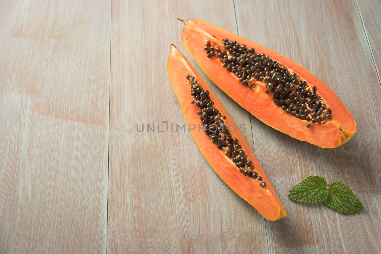 Sliced fresh papaya on wooden background. Top view with copy spa by AnaMarques