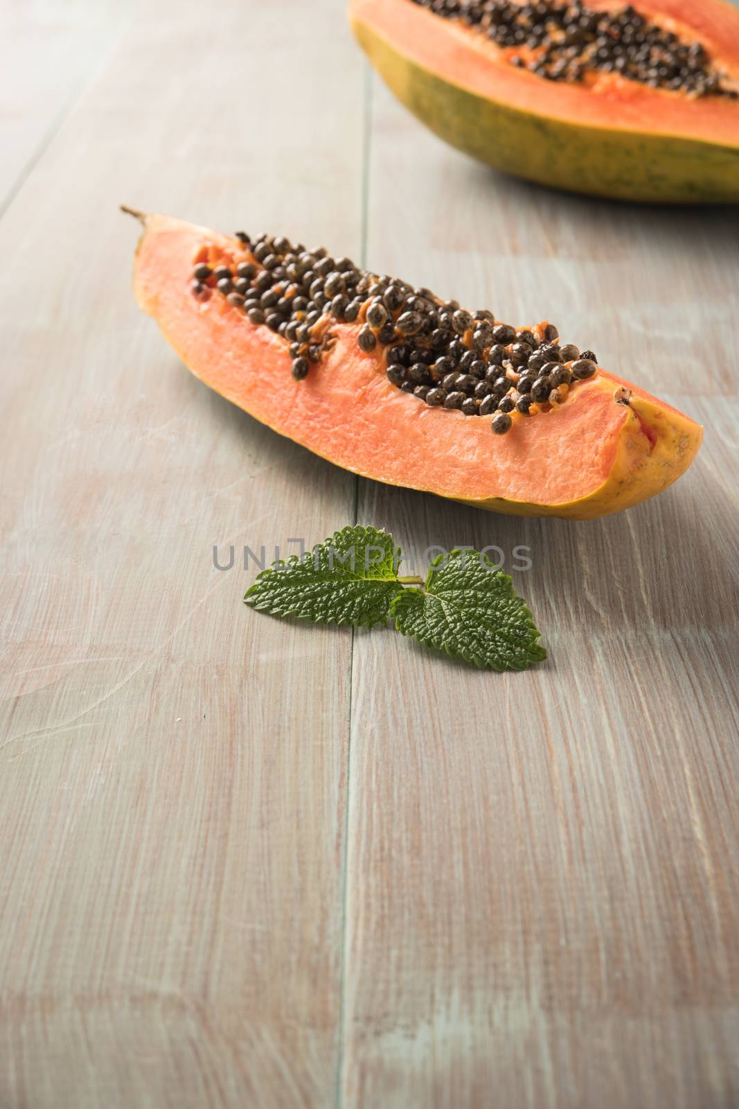 Sliced fresh papaya on wooden background. Top view with copy spa by AnaMarques