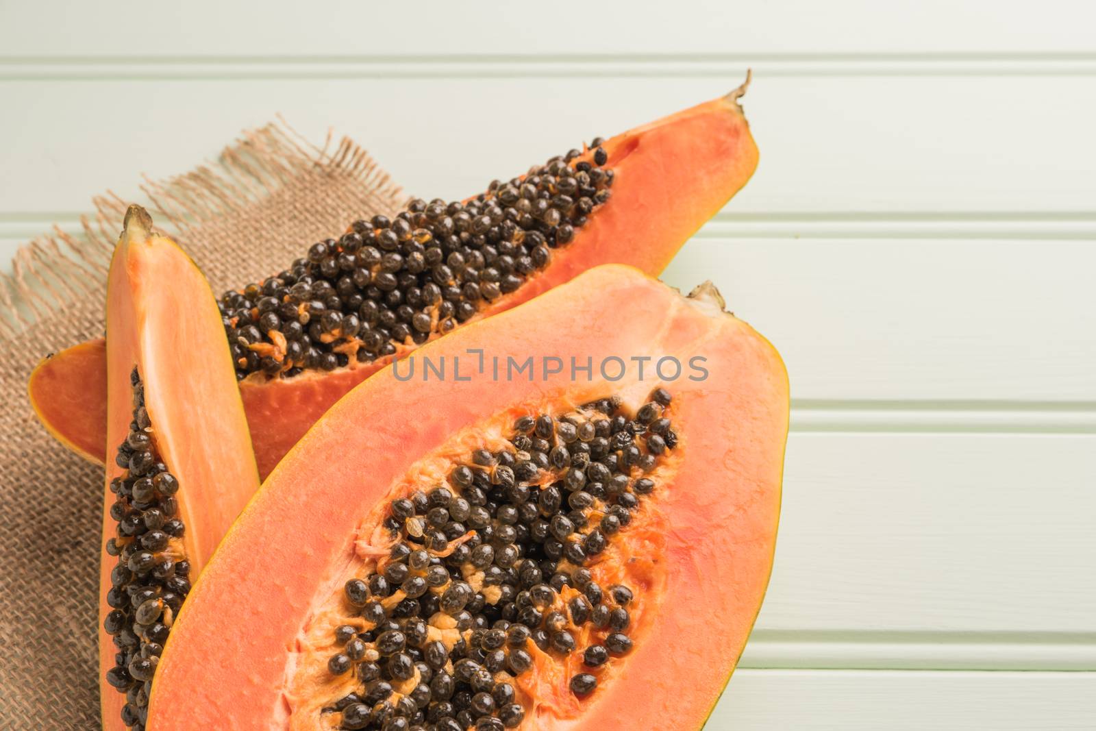 Sliced fresh papaya on wooden background. Top view with copy spa by AnaMarques