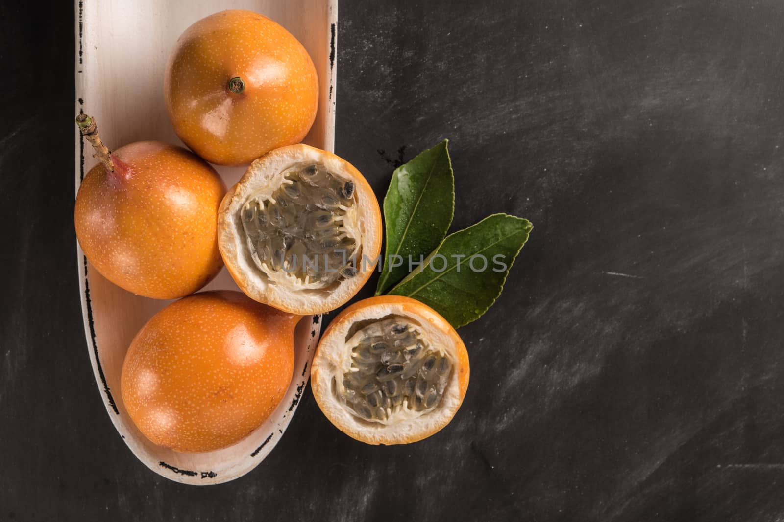 Fresh granadillas on slate with leaves. Granadillas on rustic board