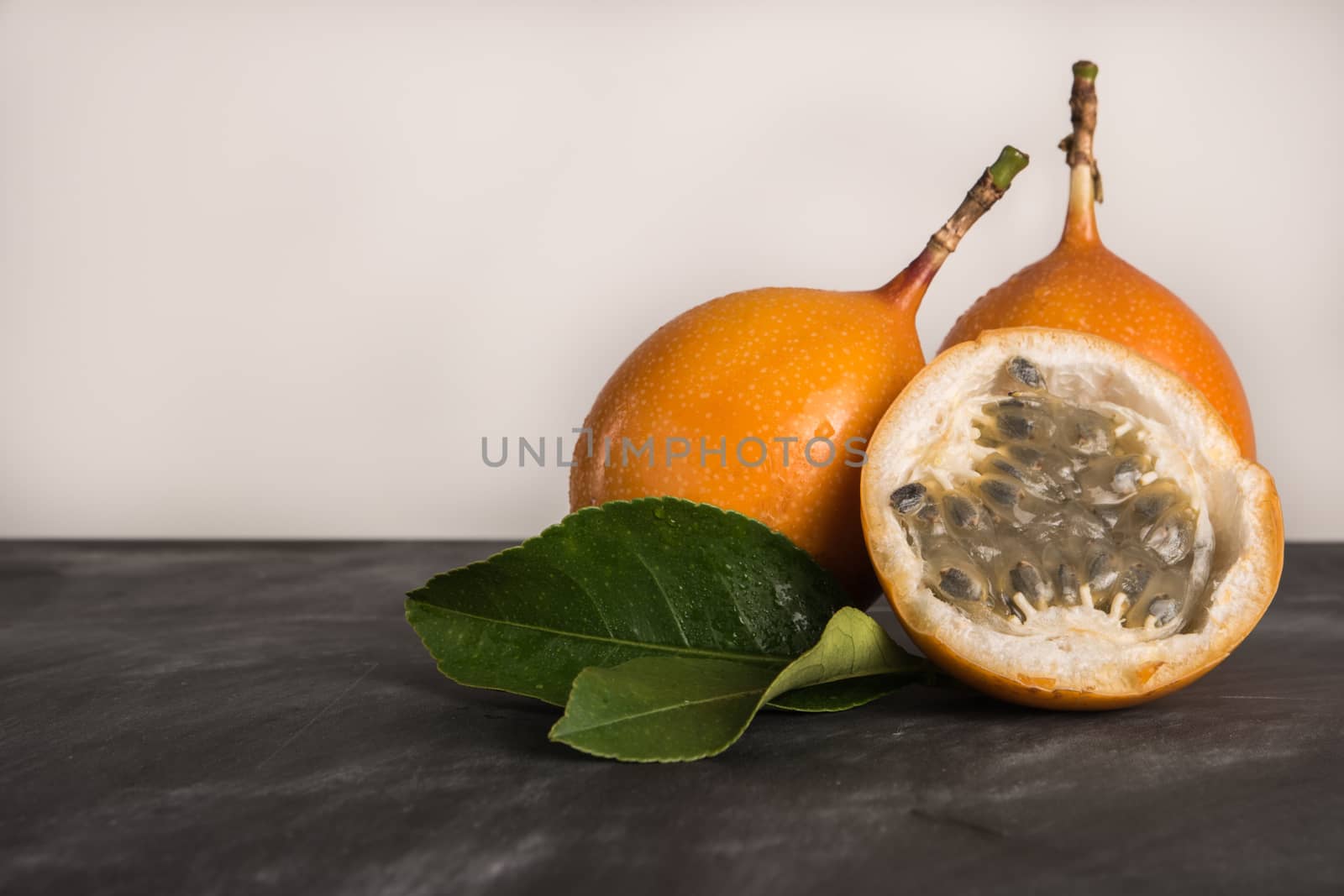 Fresh granadillas on slate with leaves. Granadillas on rustic board