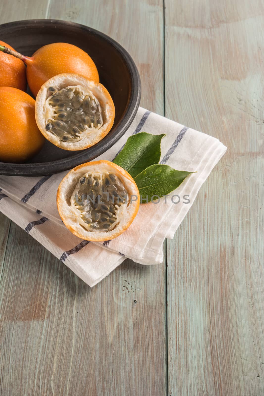 Fresh granadillas on wooden board with leaves. by AnaMarques