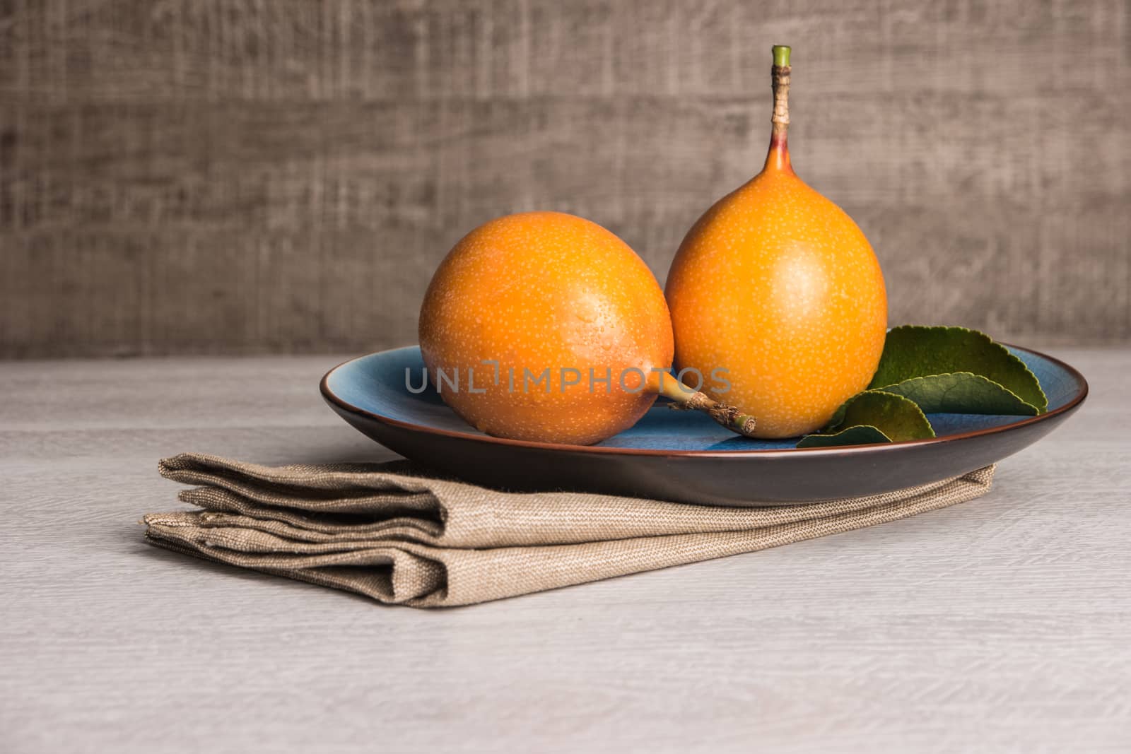 Fresh granadillas on wooden board with leaves. by AnaMarques