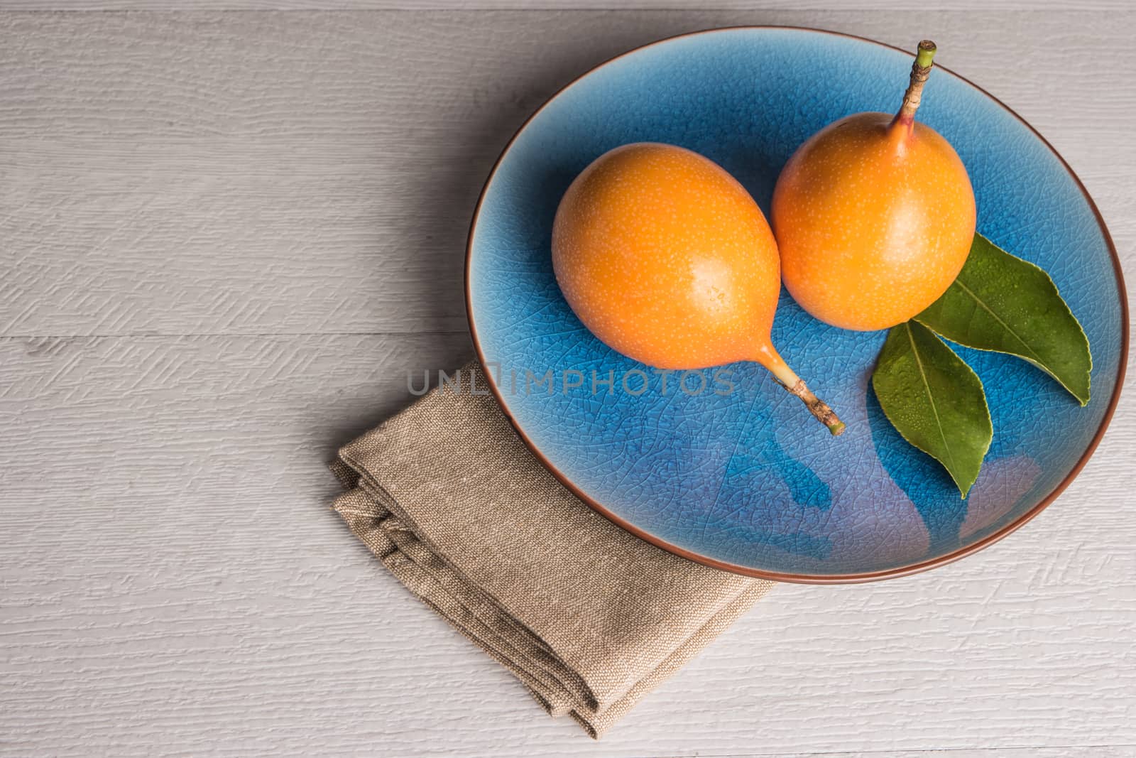 Fresh granadillas on wooden board with leaves.