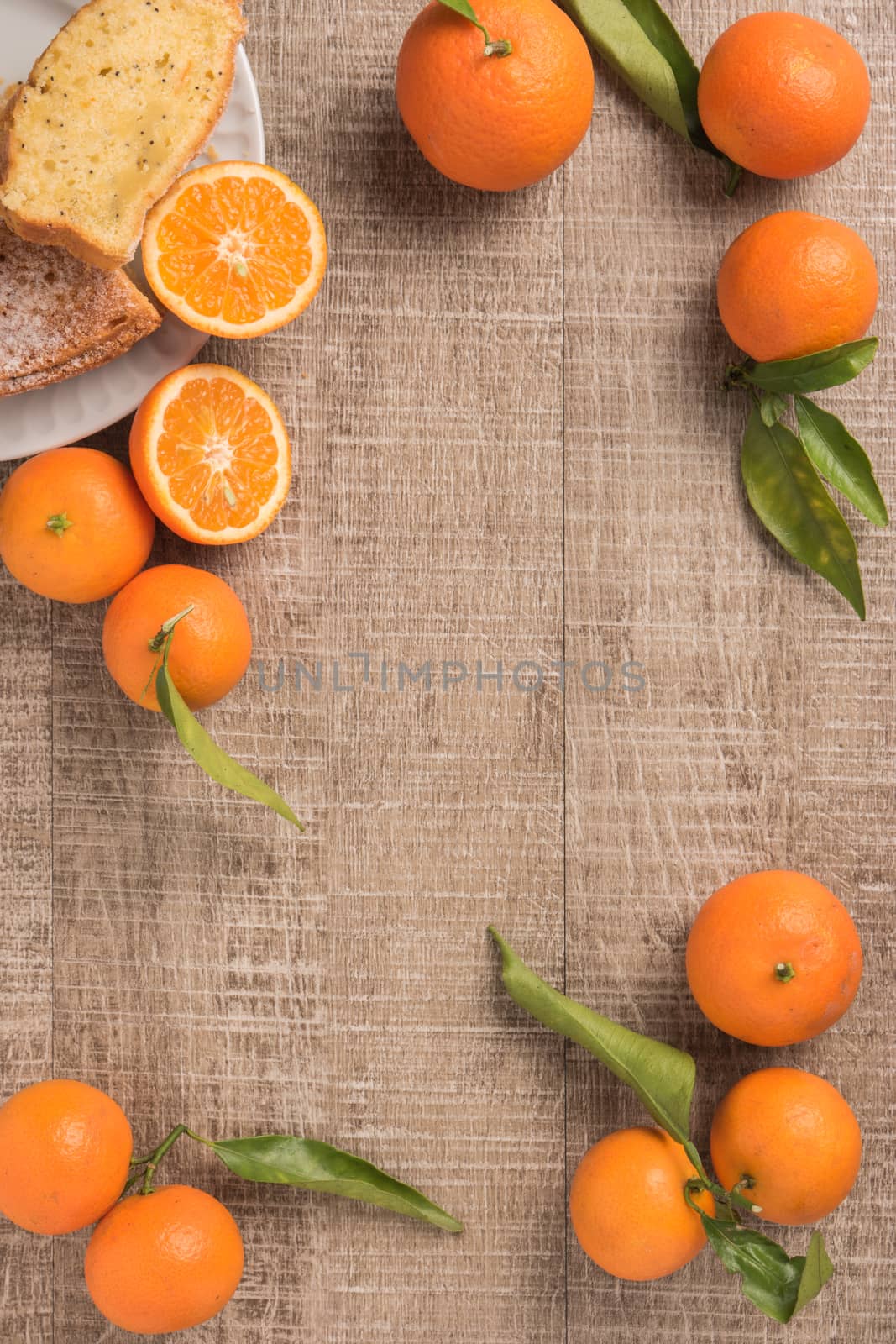 Fresh clementines and cake on wooden board with leaves. Top view with copy space.