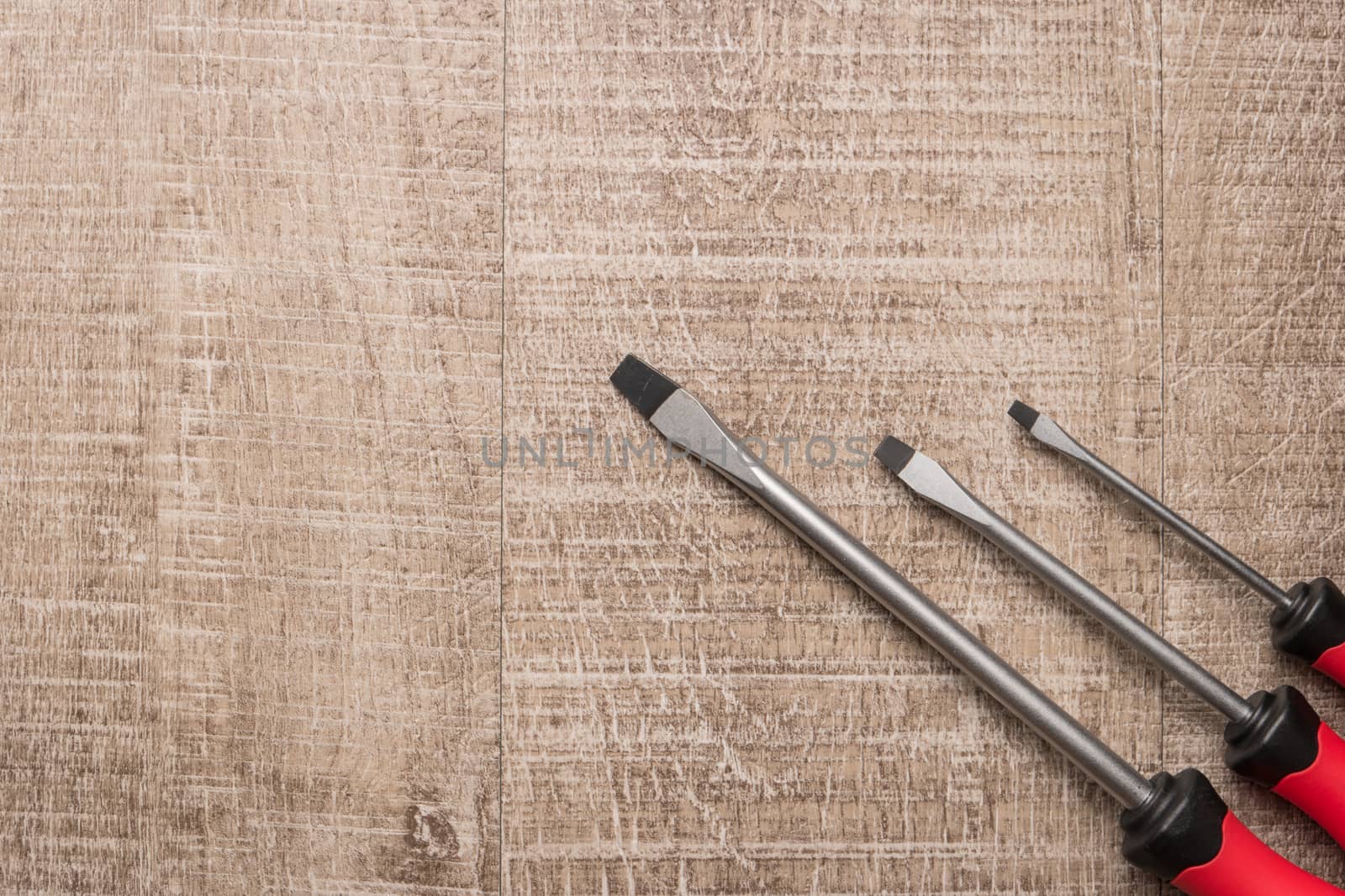 Set of screwdrivers. Tools over a wood panel. Top view with copy by AnaMarques