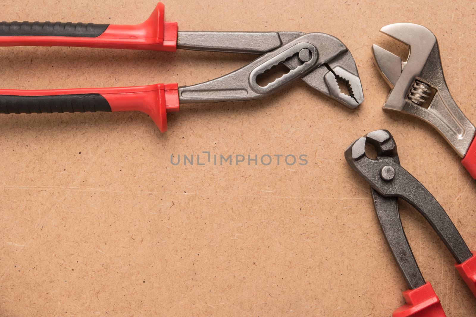 Set of pump plier, plier and wrenches. Tools over a wood panel.  by AnaMarques
