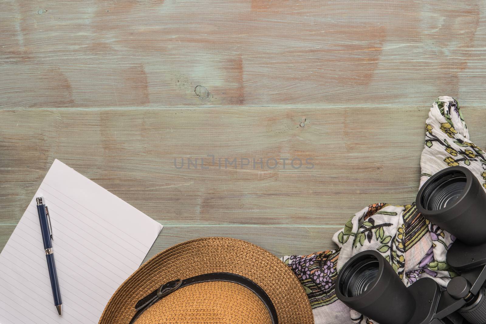 Travel, summer vacation, tourism and objects concept - close up of binoculars, hat, pen, paper and scarf on wooden table. Top view with copy space.