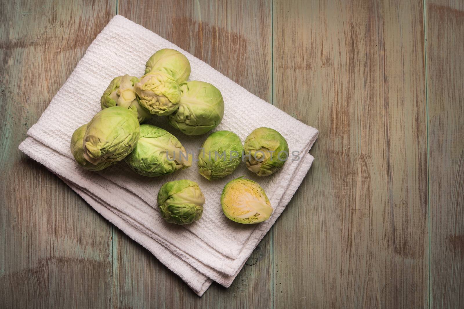 Fresh brussel sprouts over rustic wooden texture. Top view with copy space.