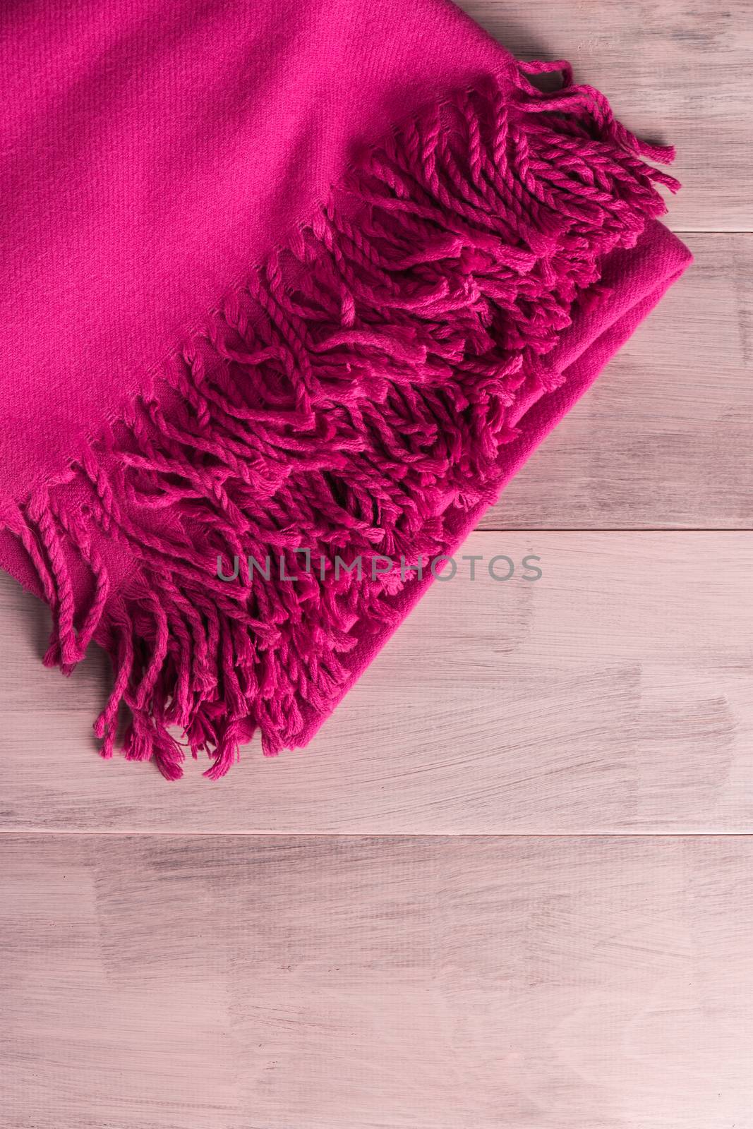 Woolen soft and worm scarf on rustic wooden background. Top view with copy space