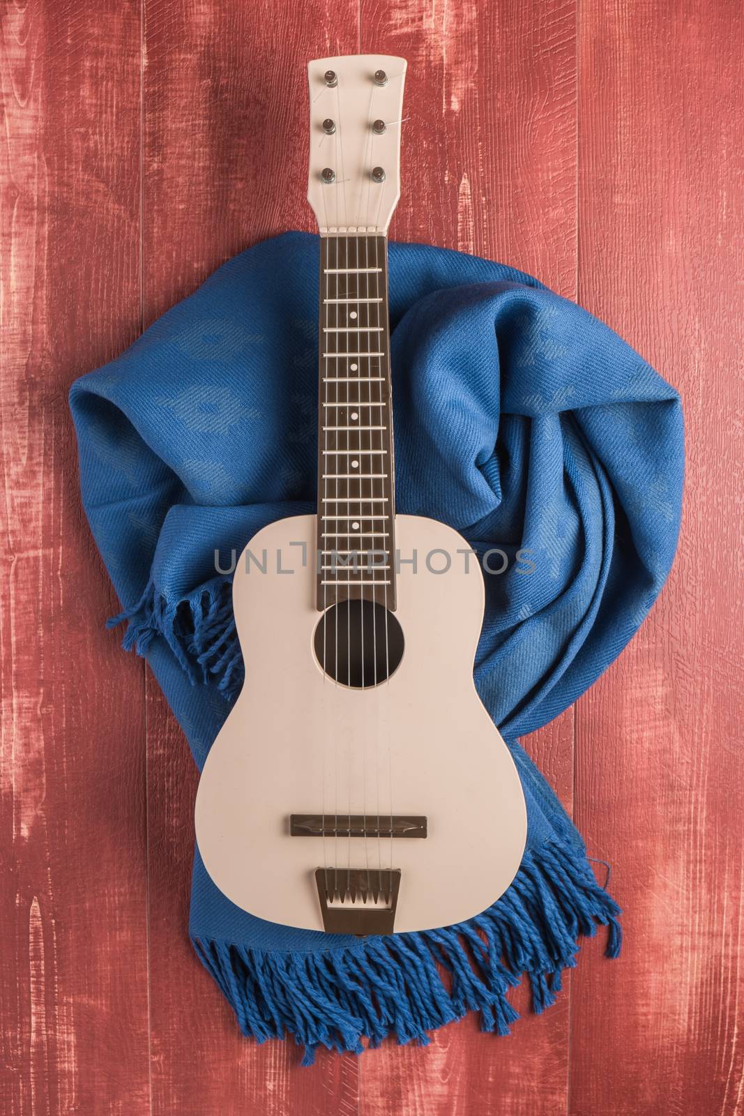 Guitar and blanket on rustic wooden background texture by AnaMarques