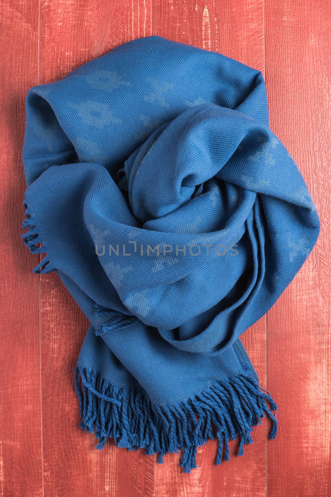 Woolen soft and worm scarf on rustic wooden background. Top view with copy space