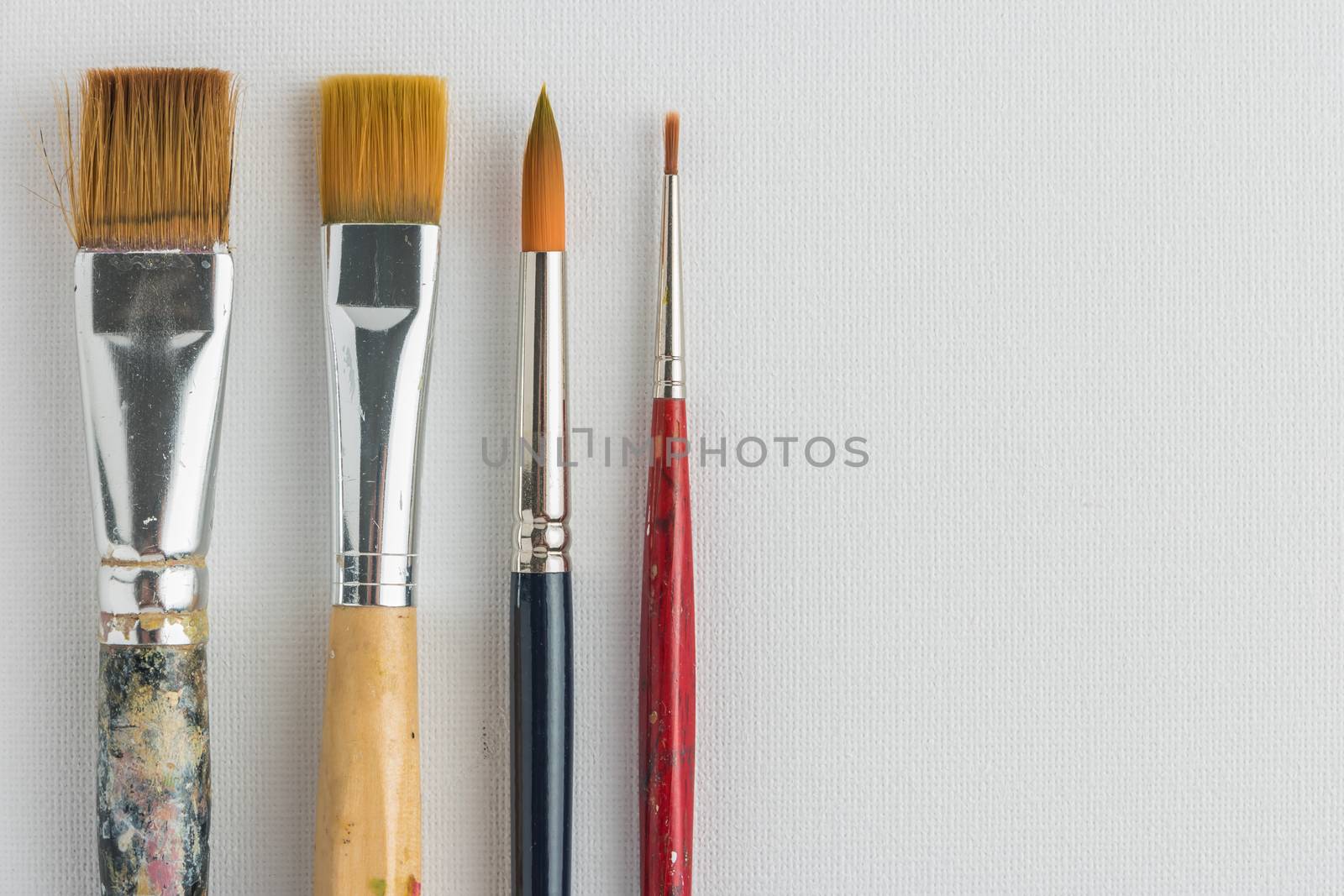 Artist paint brushes on canvas background. Top view with copy space.