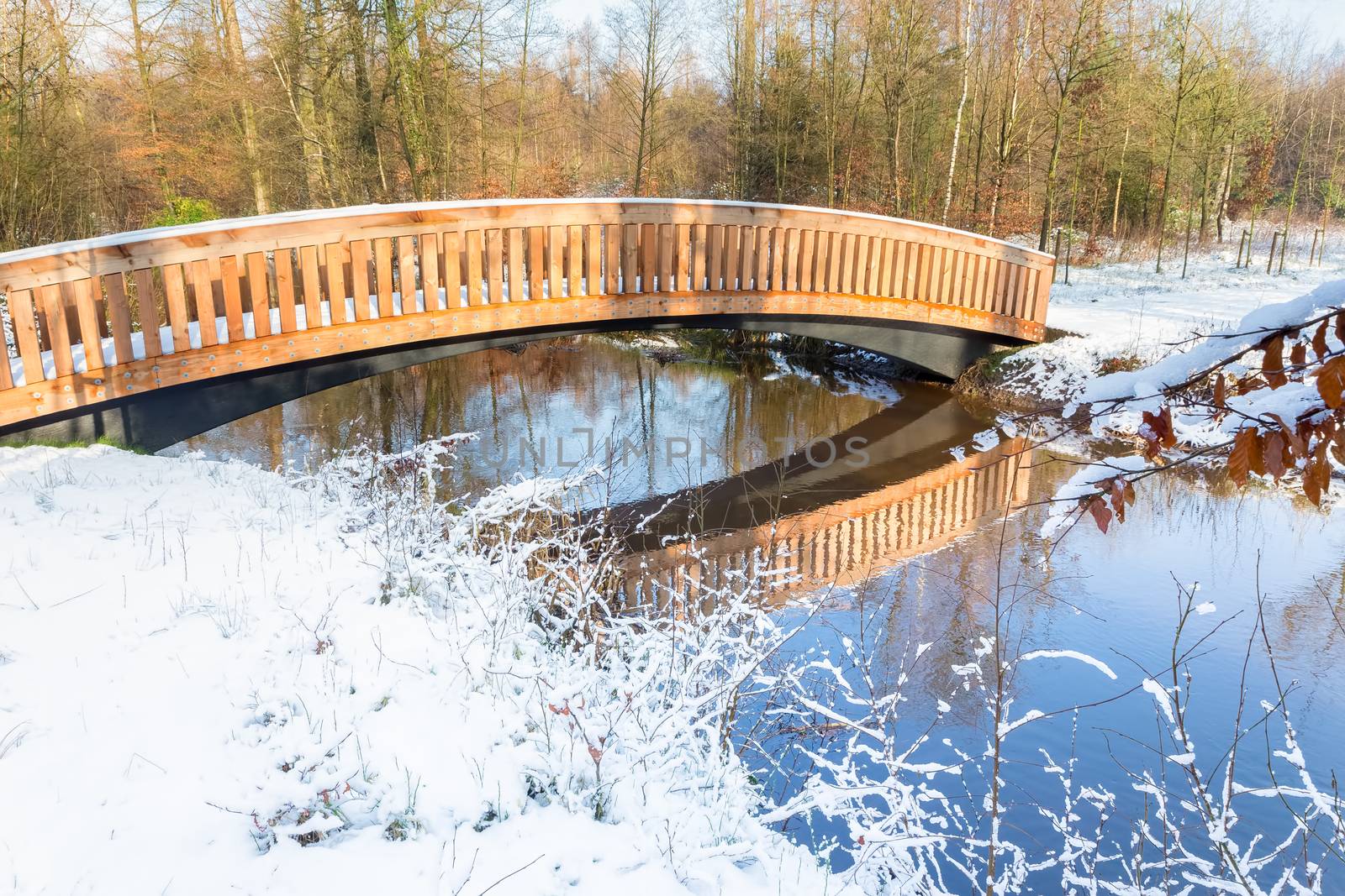Wooden pedestrian bridge with snow and water in winter  landscape