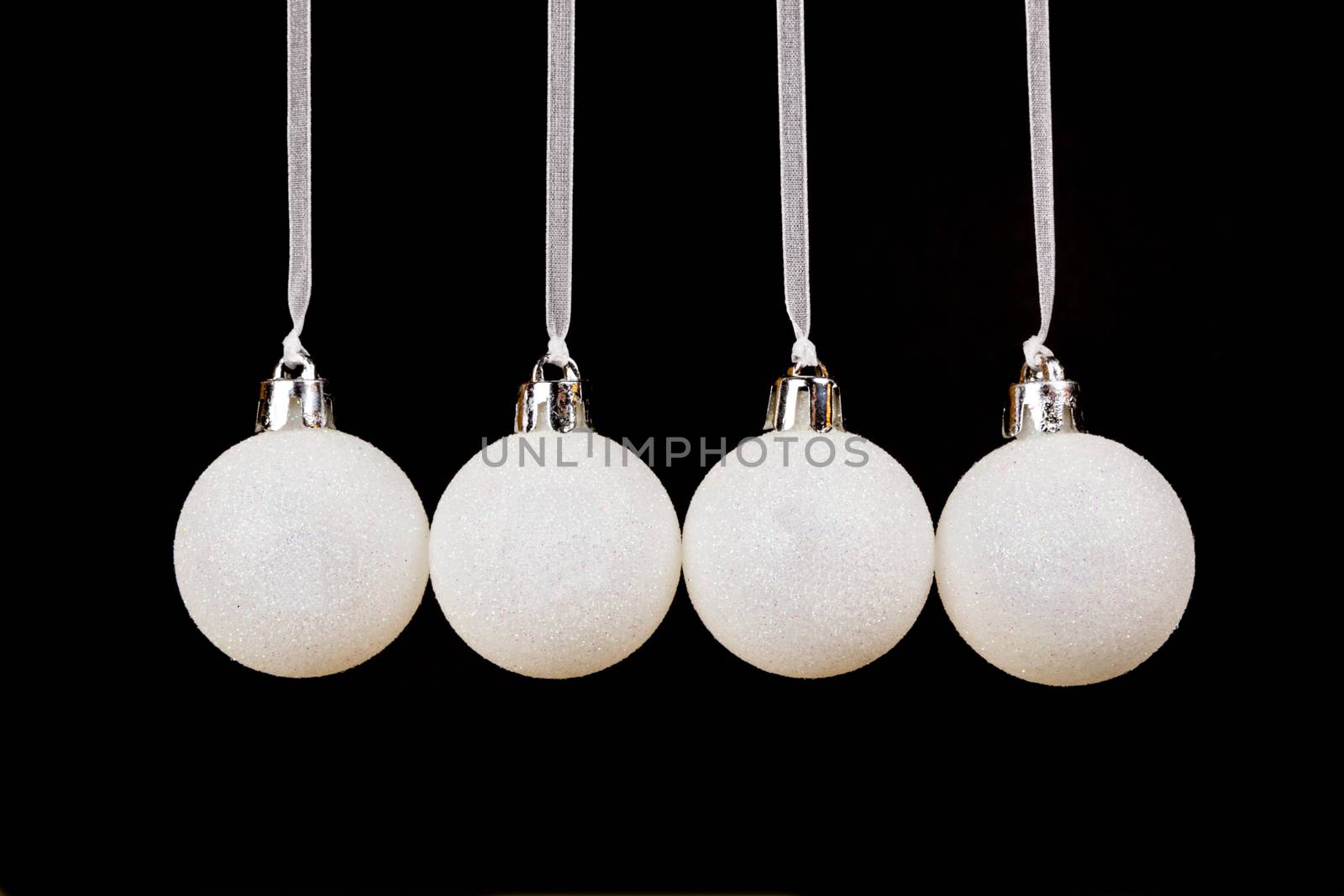 White christmas balls hanging in a row on black background by BenSchonewille