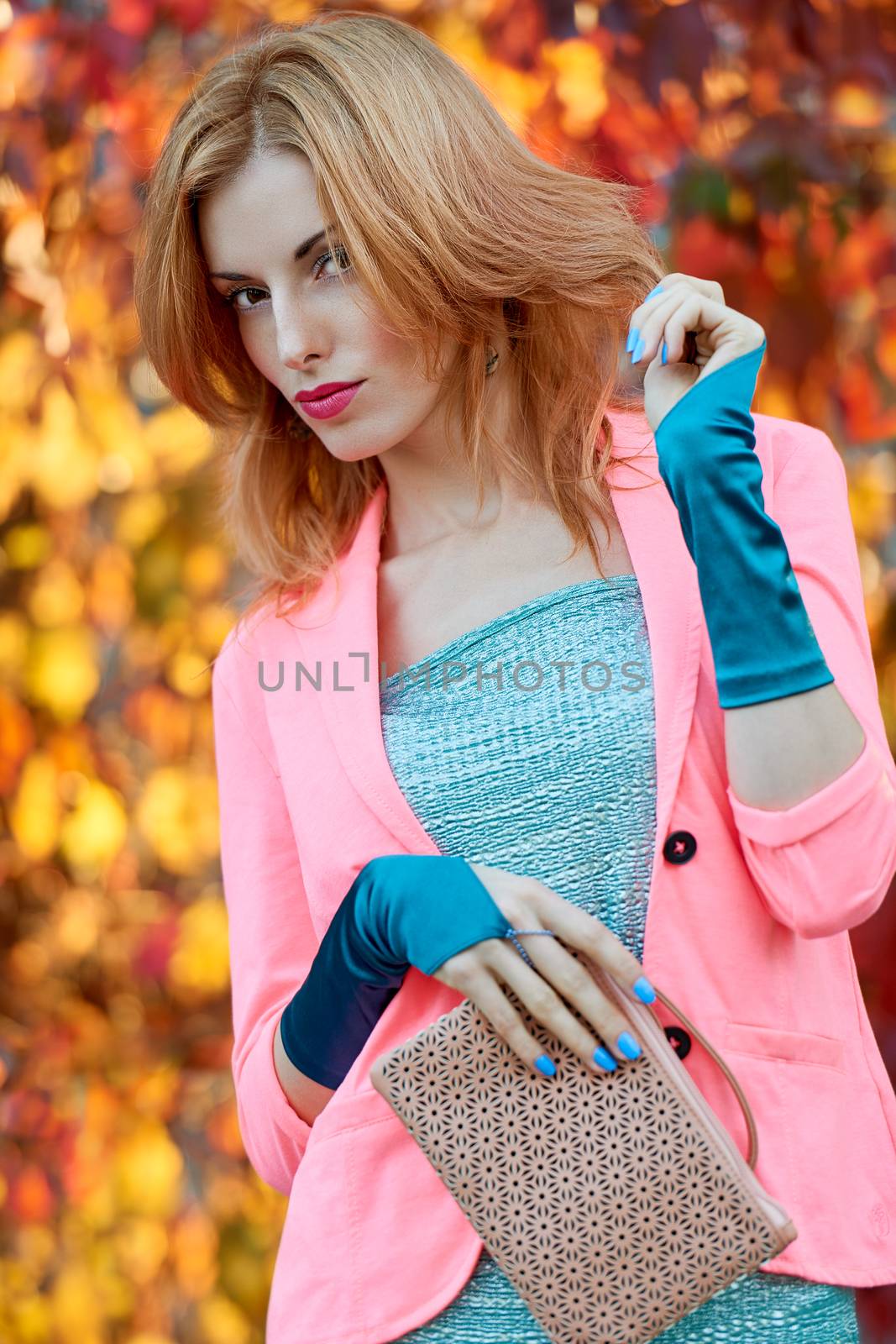 Fashion urban beauty people, woman, outdoor.Playful glamor hipster redhead girl in stylish vivid jacket, gloves with trandy clutch. Sunny day, autumn orange bokeh.Creative unusual, park, lifestyle