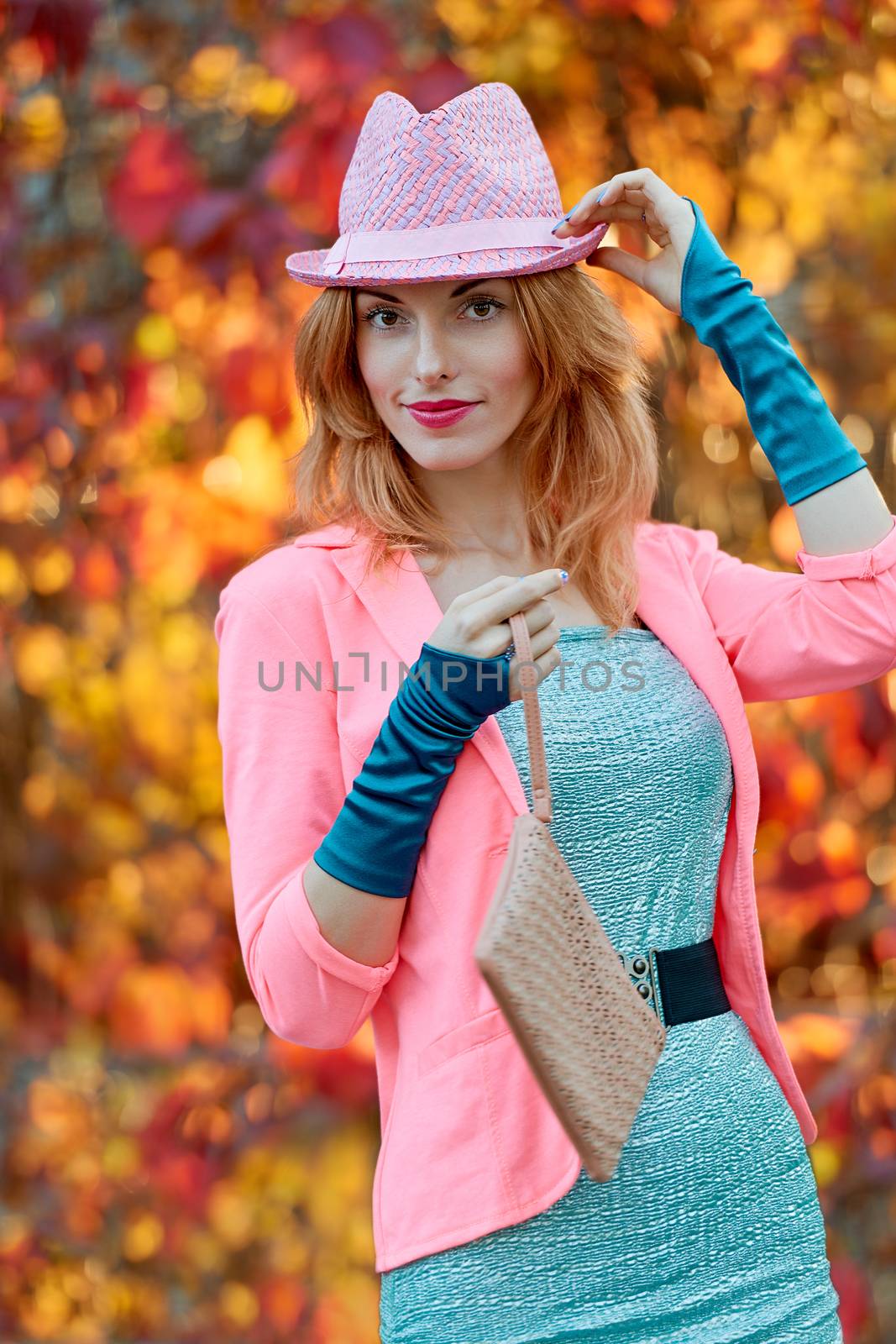 Fashion urban beauty people, smiling woman, outdoor. Playful glamor hipster redhead girl. Stylish hat vivid jacket, gloves and clutch. Sunny day, autumn orange bokeh. Creative unusual, park, lifestyle
