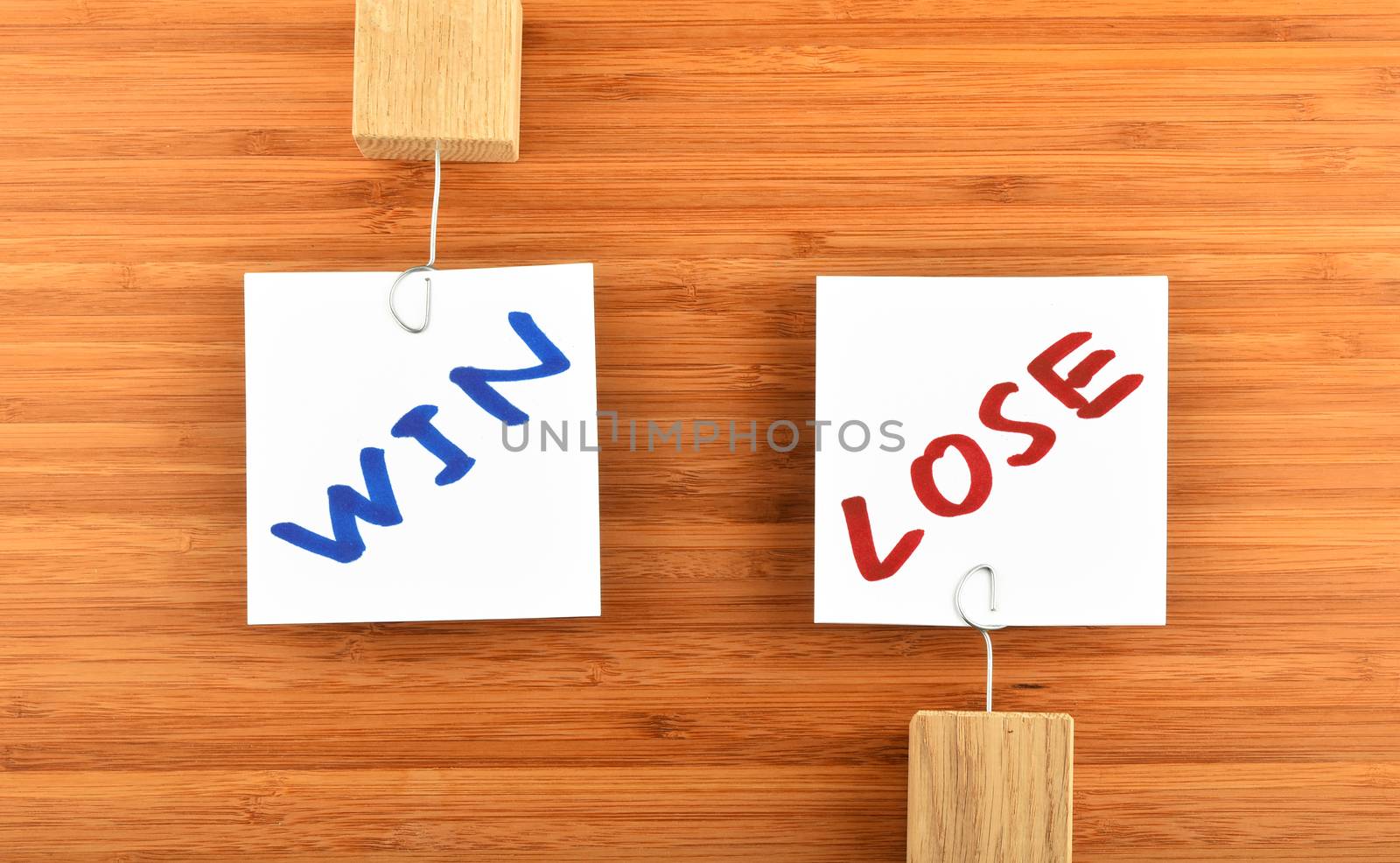 Win lose, two white paper notes with marker hand written words, wooden holders in different directions on bamboo wooden background for presentation