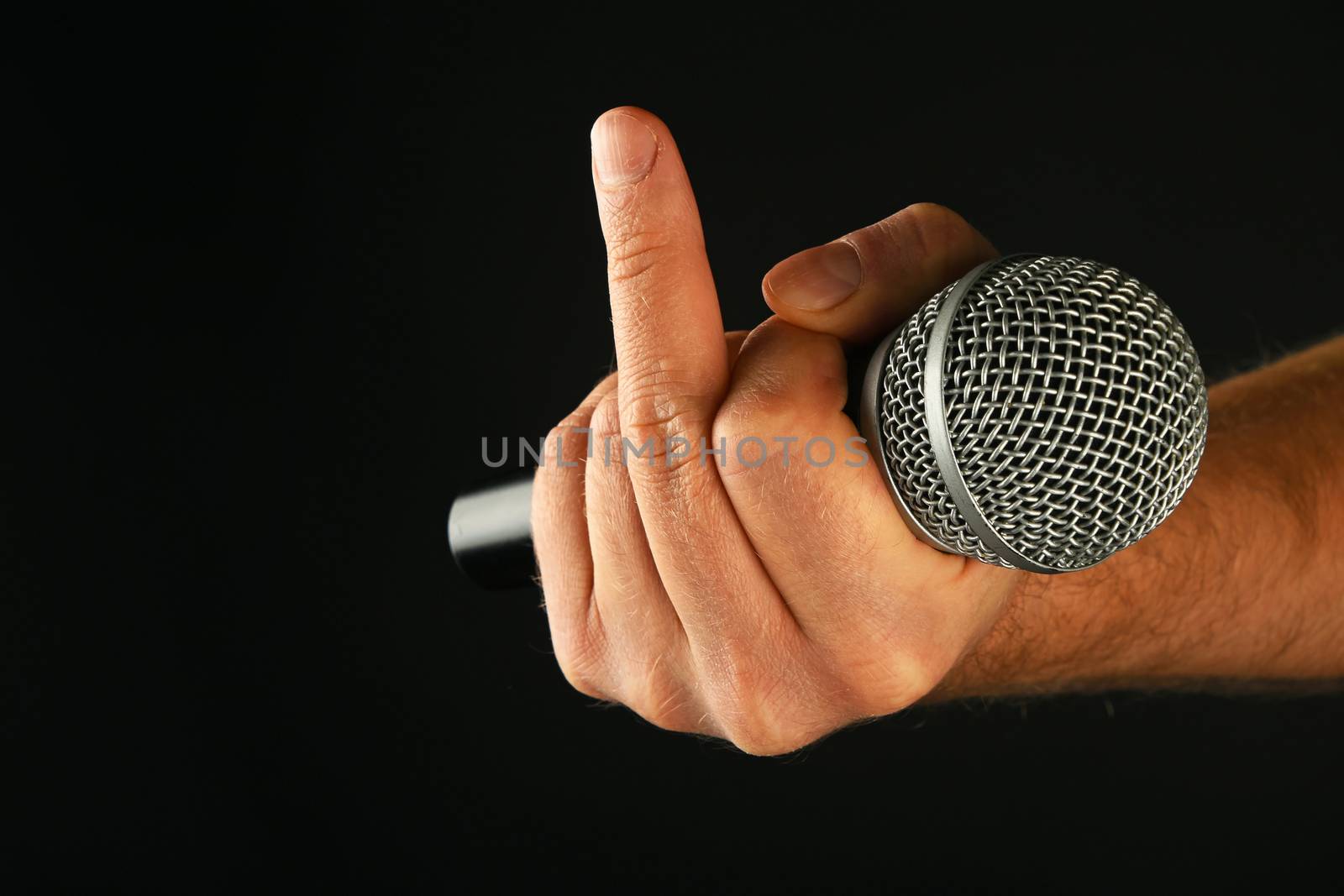 Male hand holding microphone with finger fuck off insult ignore gesture on black background
