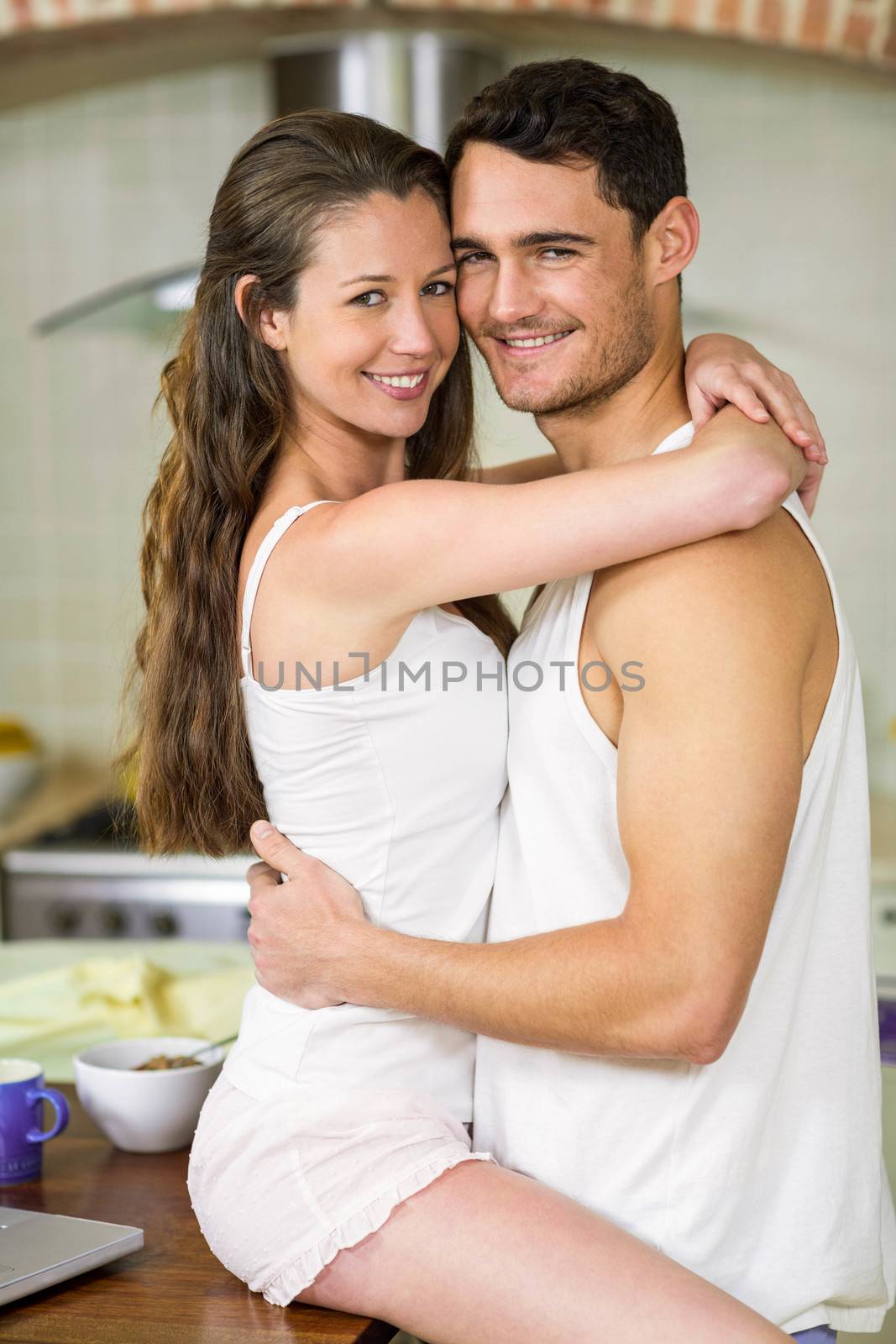 Portrait of romantic young couple cuddling on kitchen worktop