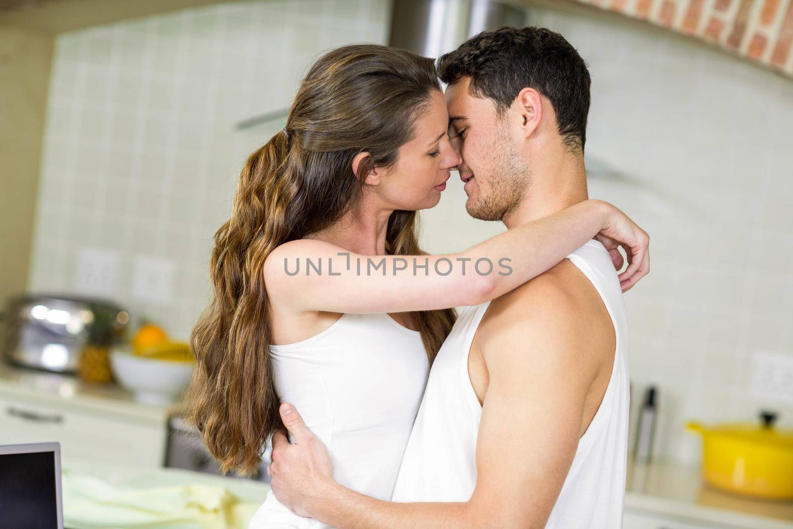 Close-up of romantic young couple cuddling in kitchen