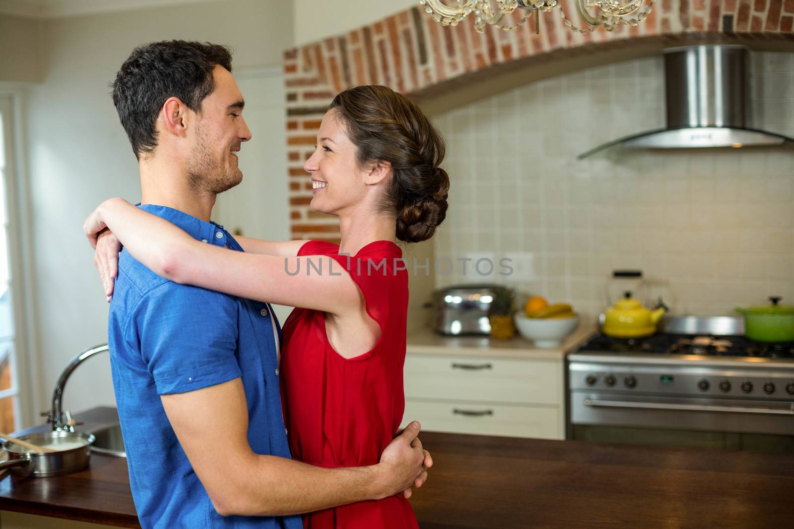 Romantic couple standing face to face and embracing each other in kitchen