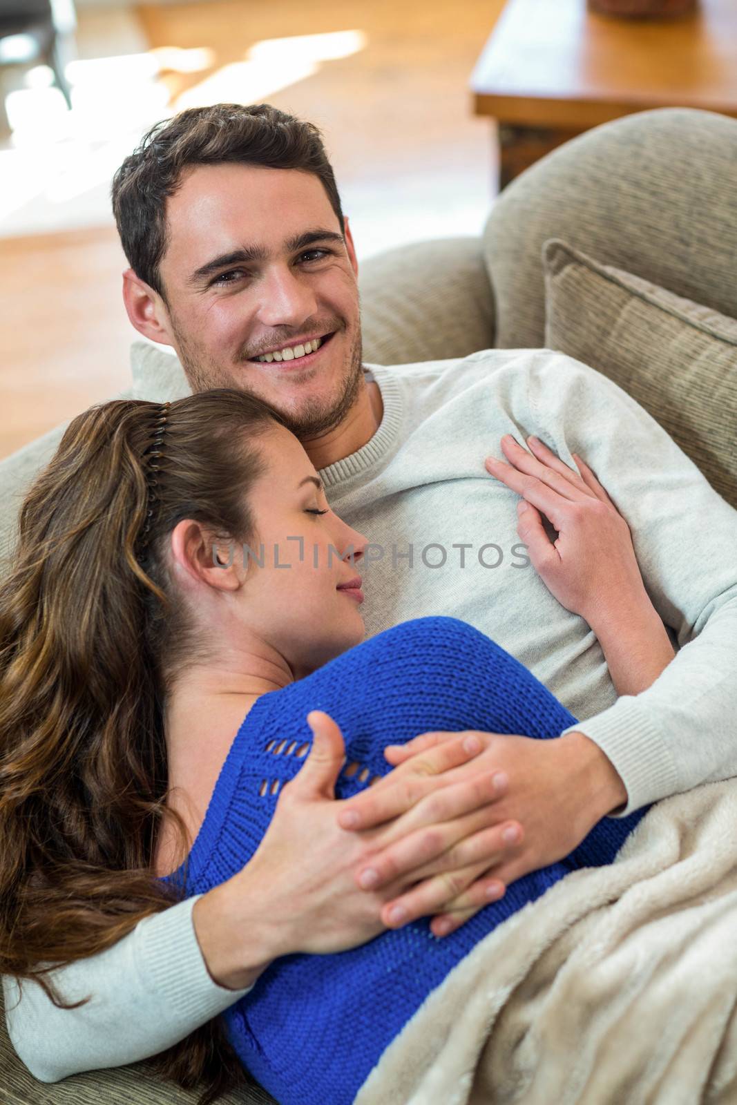 Romantic young couple cuddling on sofa in living room