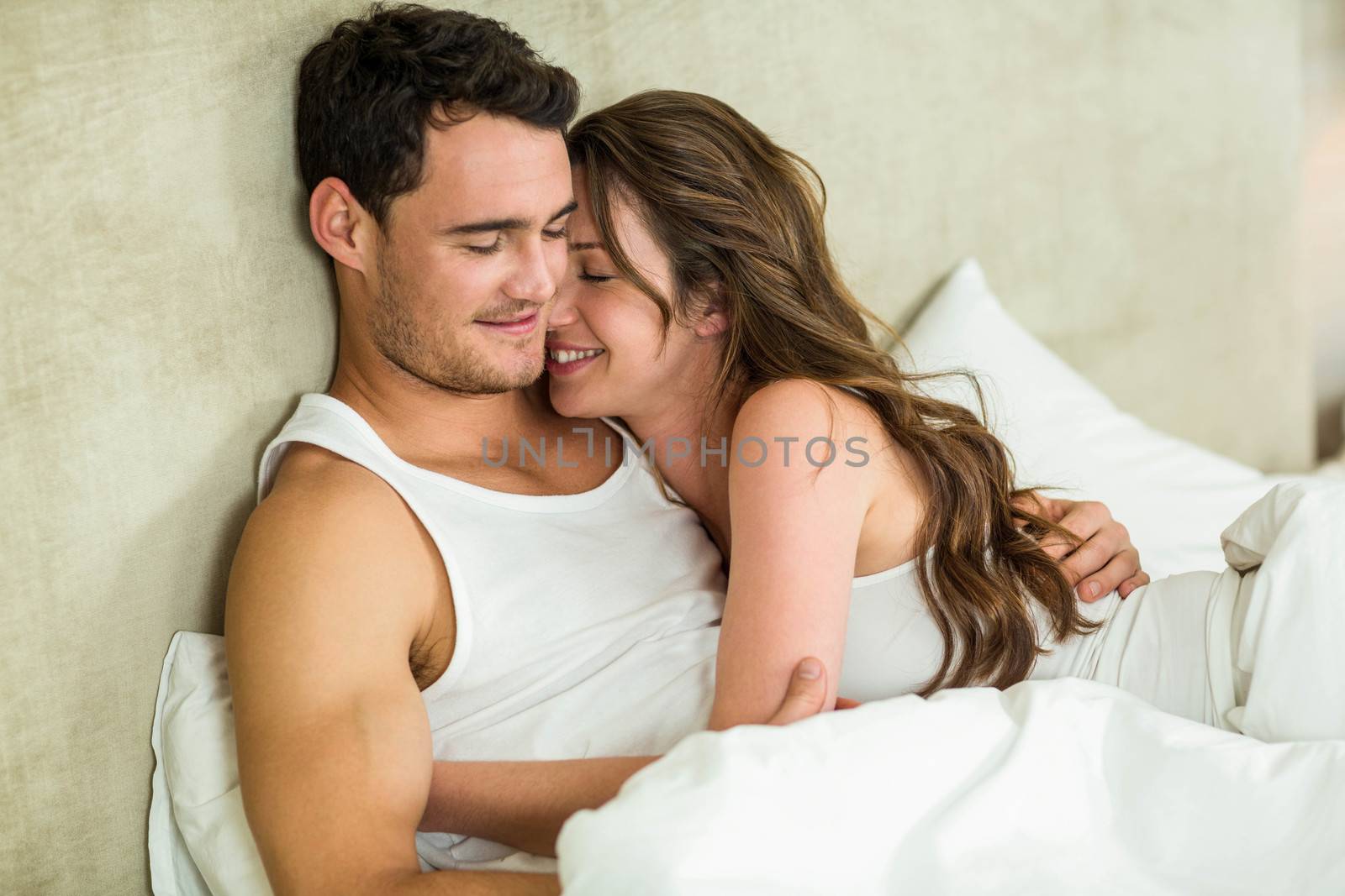 Romantic couple cuddling on bed in bedroom
