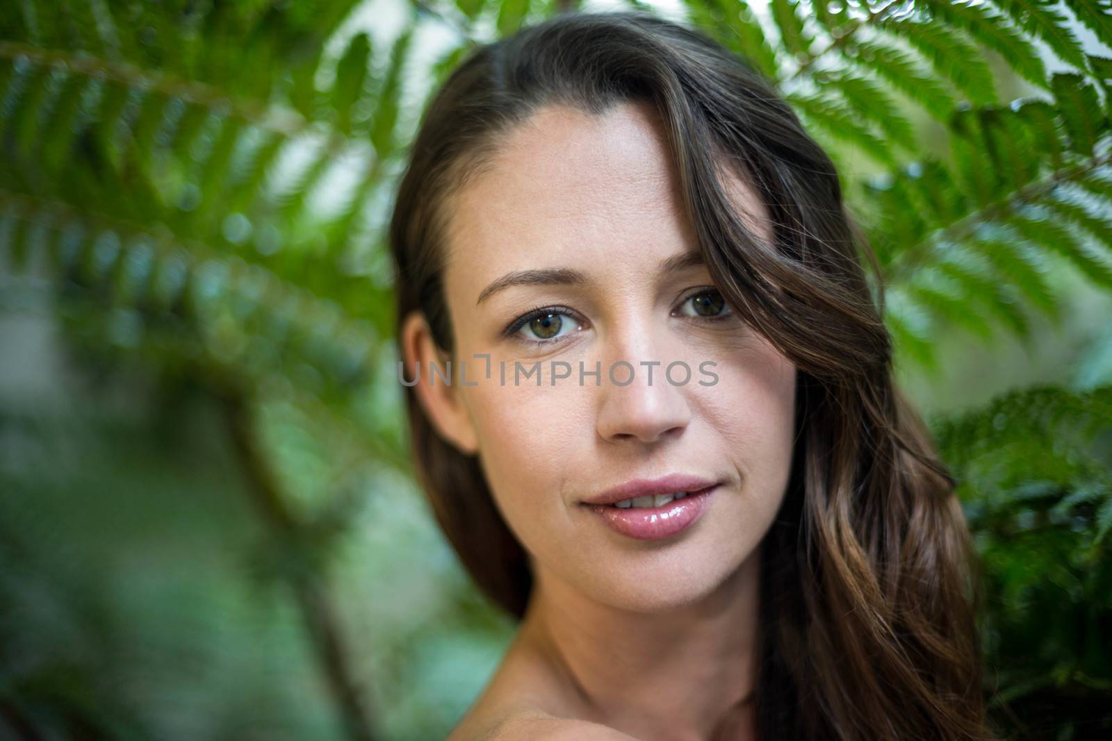 Portrait of beautiful woman standing outdoors against green plants
