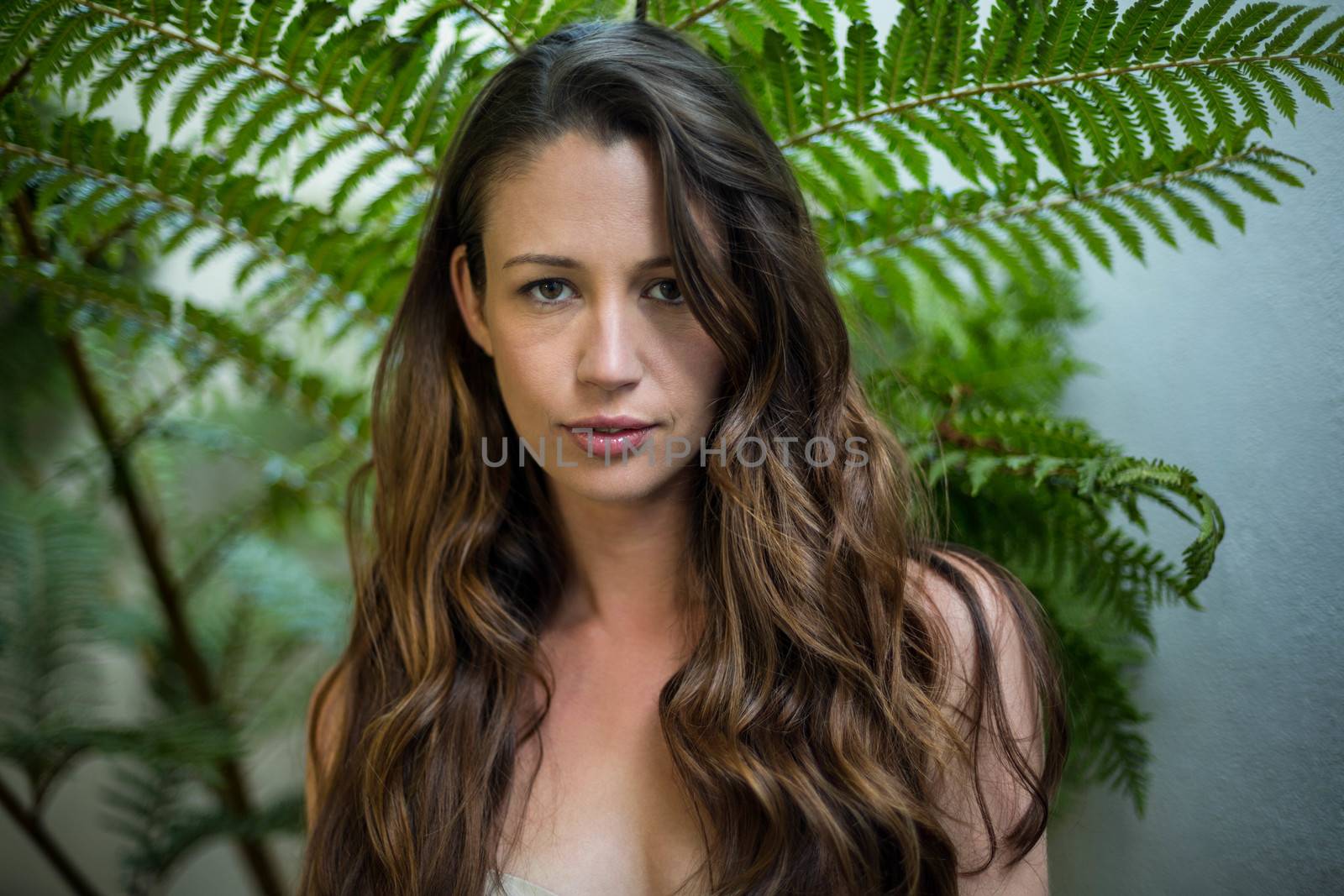 Portrait of beautiful woman standing outdoors against green plants